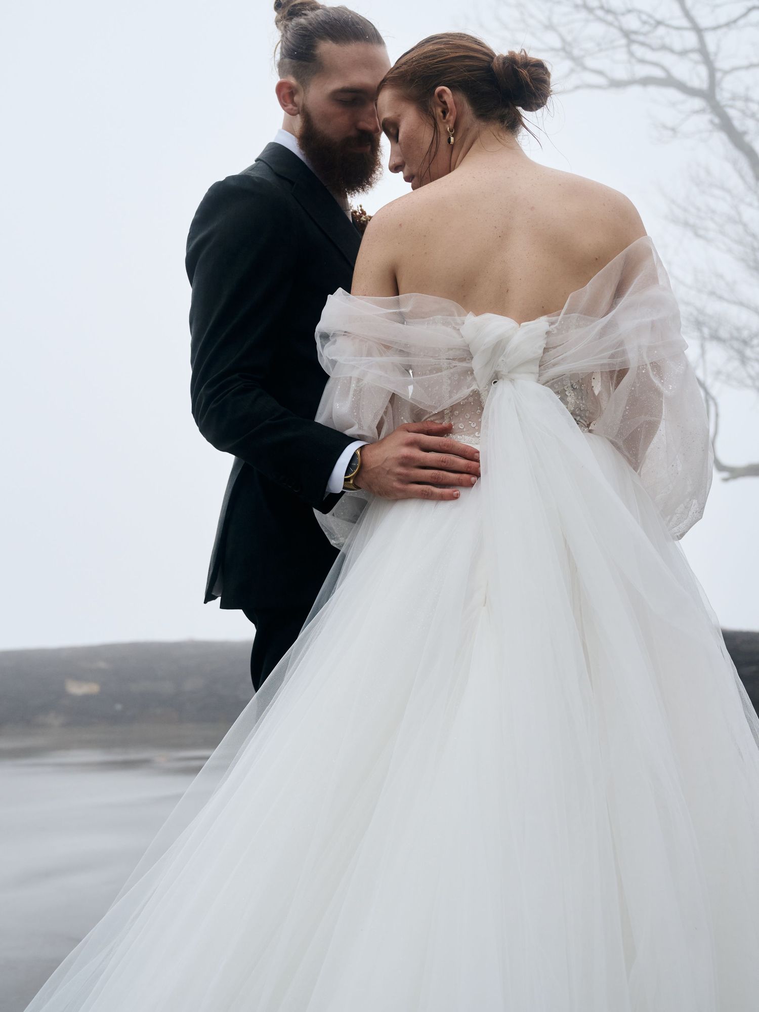 Atmospheric wedding photo with white tulle gown against misty background.
