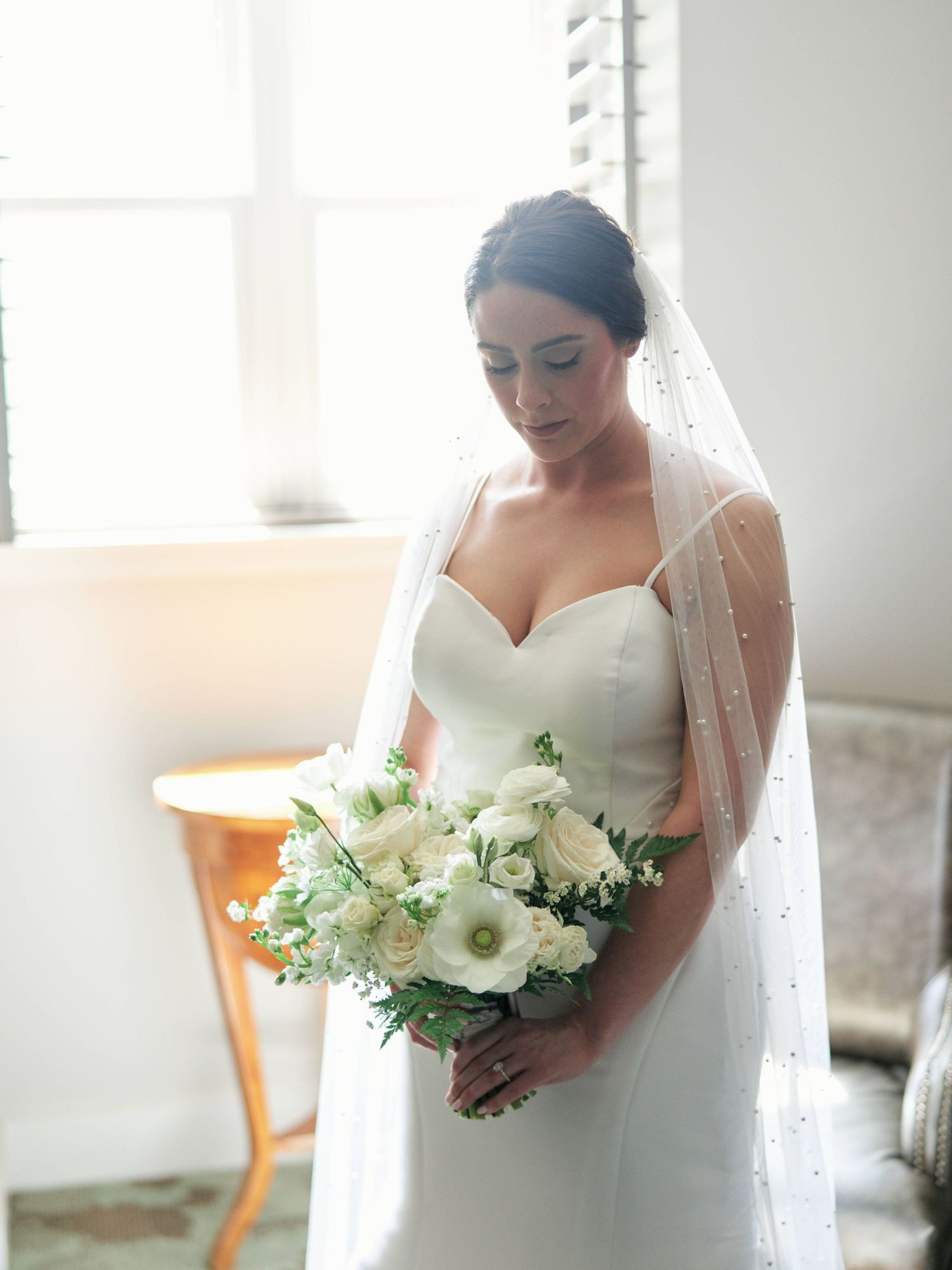 Elegant bridal portrait with white bouquet near window light.