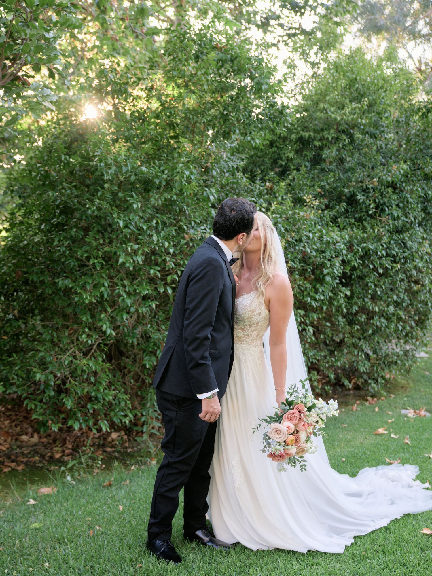 Romantic garden wedding moment with lush greenery backdrop.