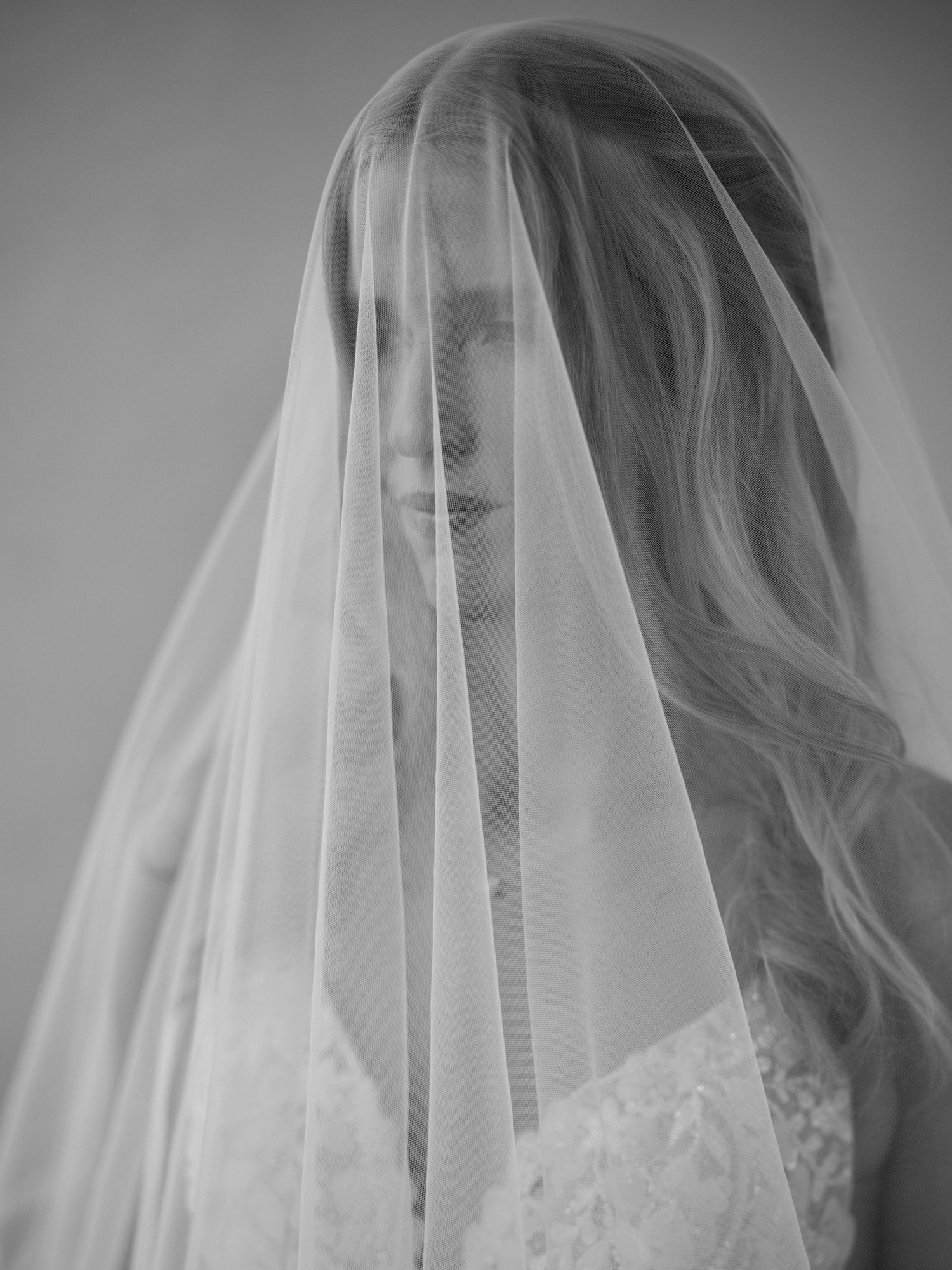 Ethereal black and white bridal portrait with flowing sheer veil.