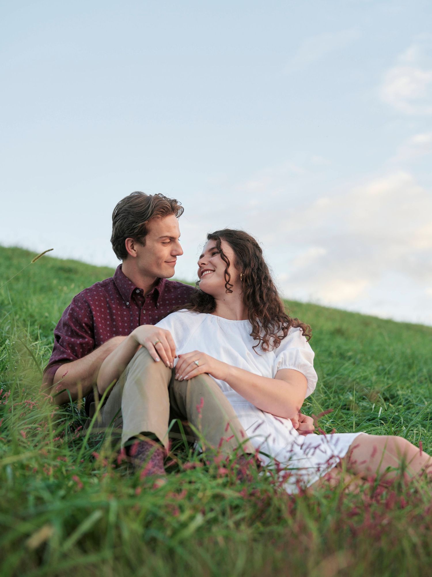 couple sitting on a green field in Raleigh, NC.