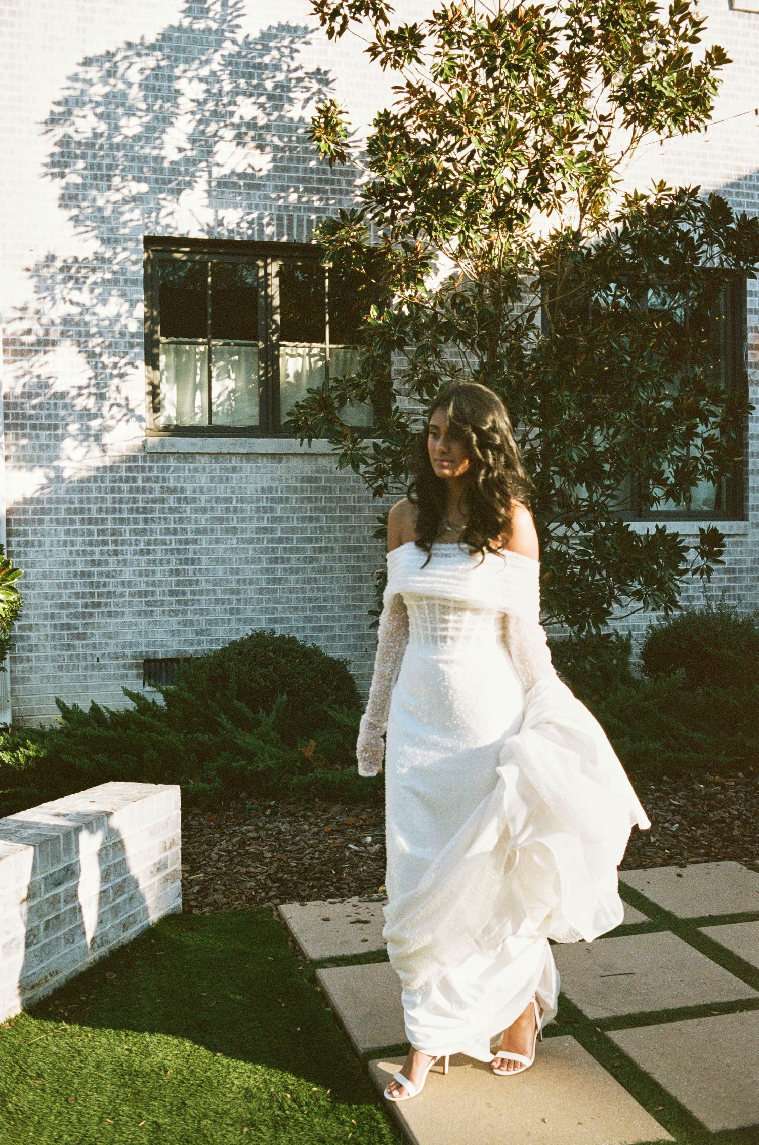 Bride walking outside the venue holding her dress.