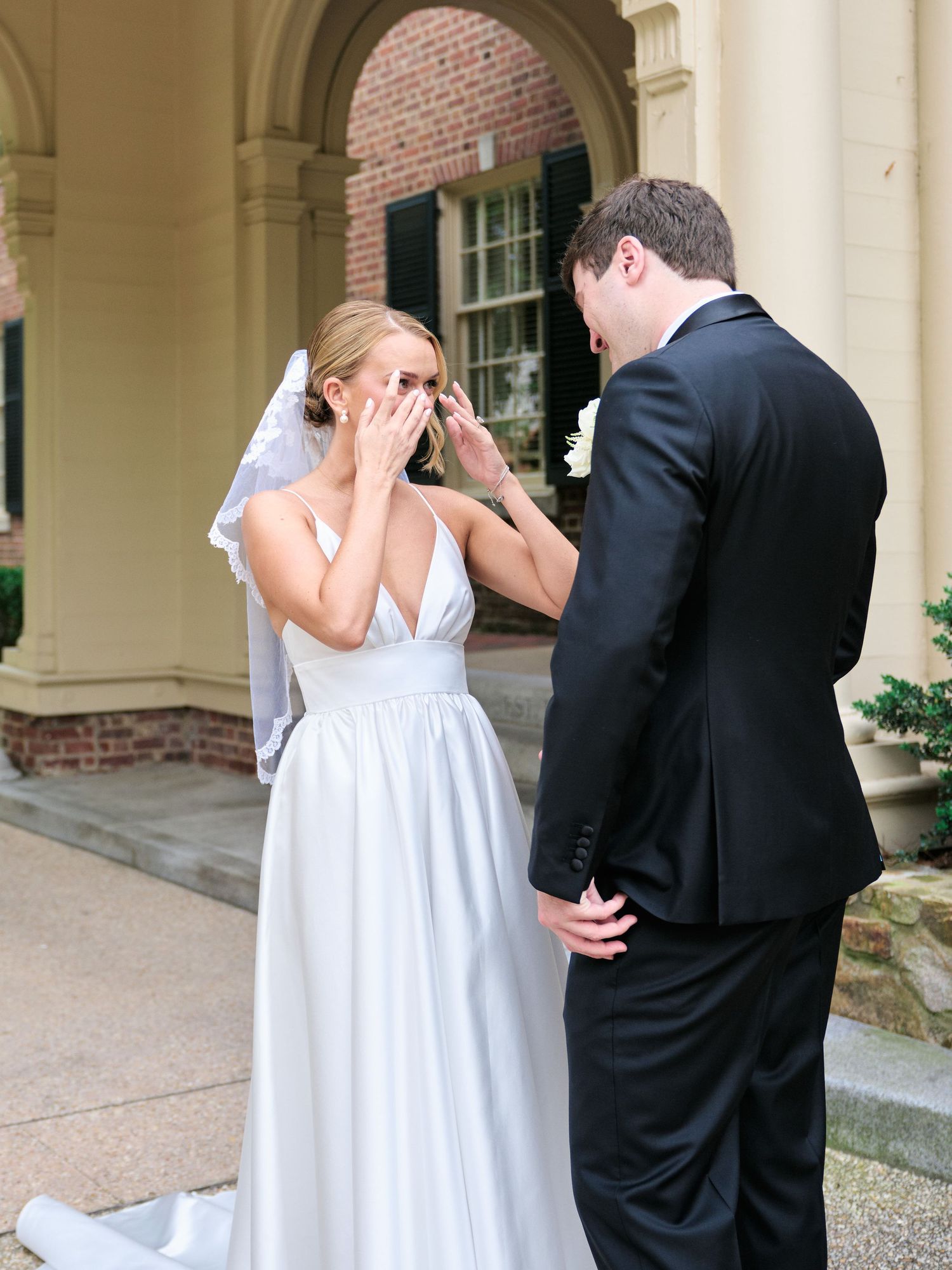 An emotional first look moment between newlyweds under a covered walkway.