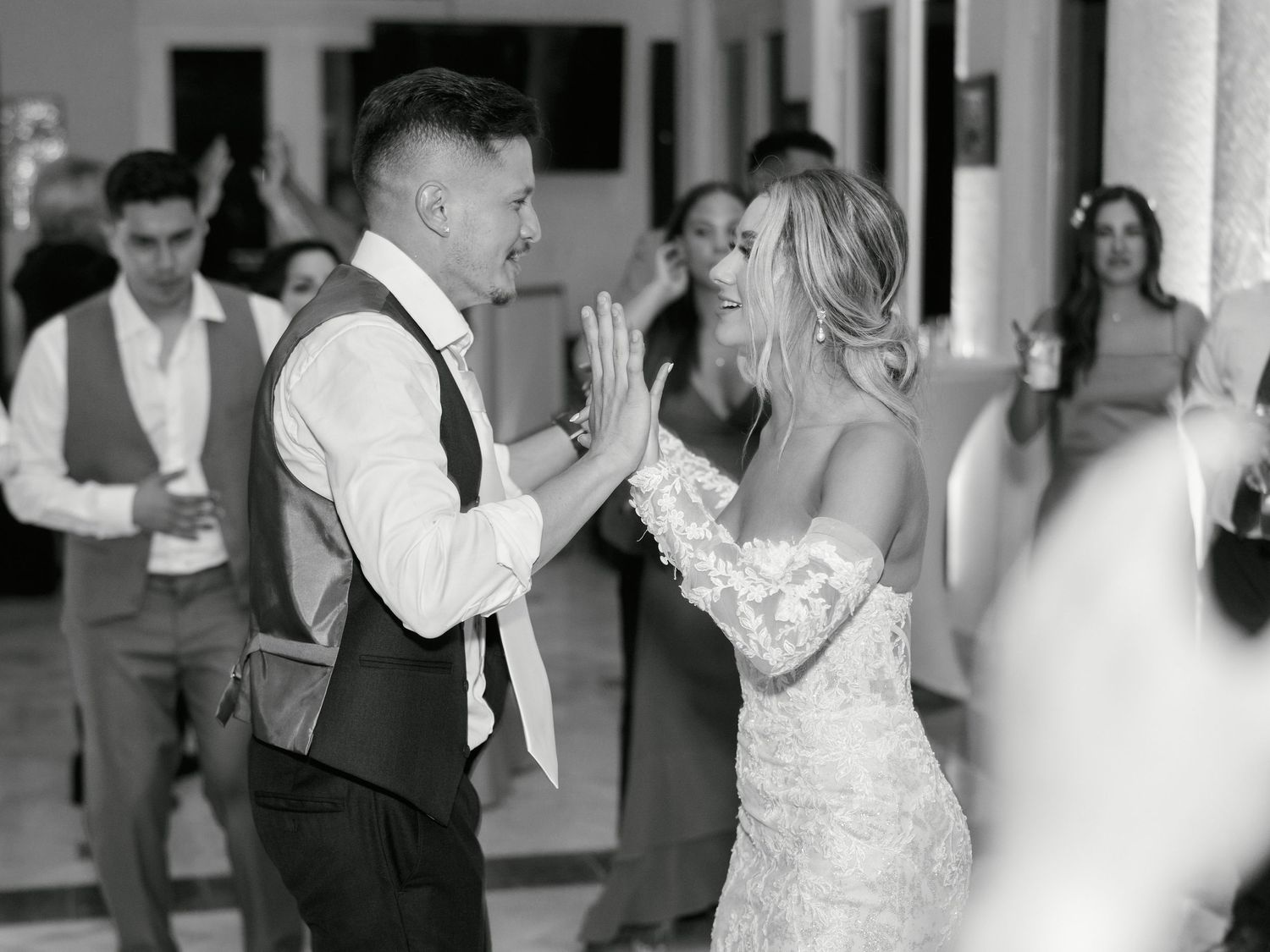 Candid black and white photograph of a celebratory moment during a wedding reception.
