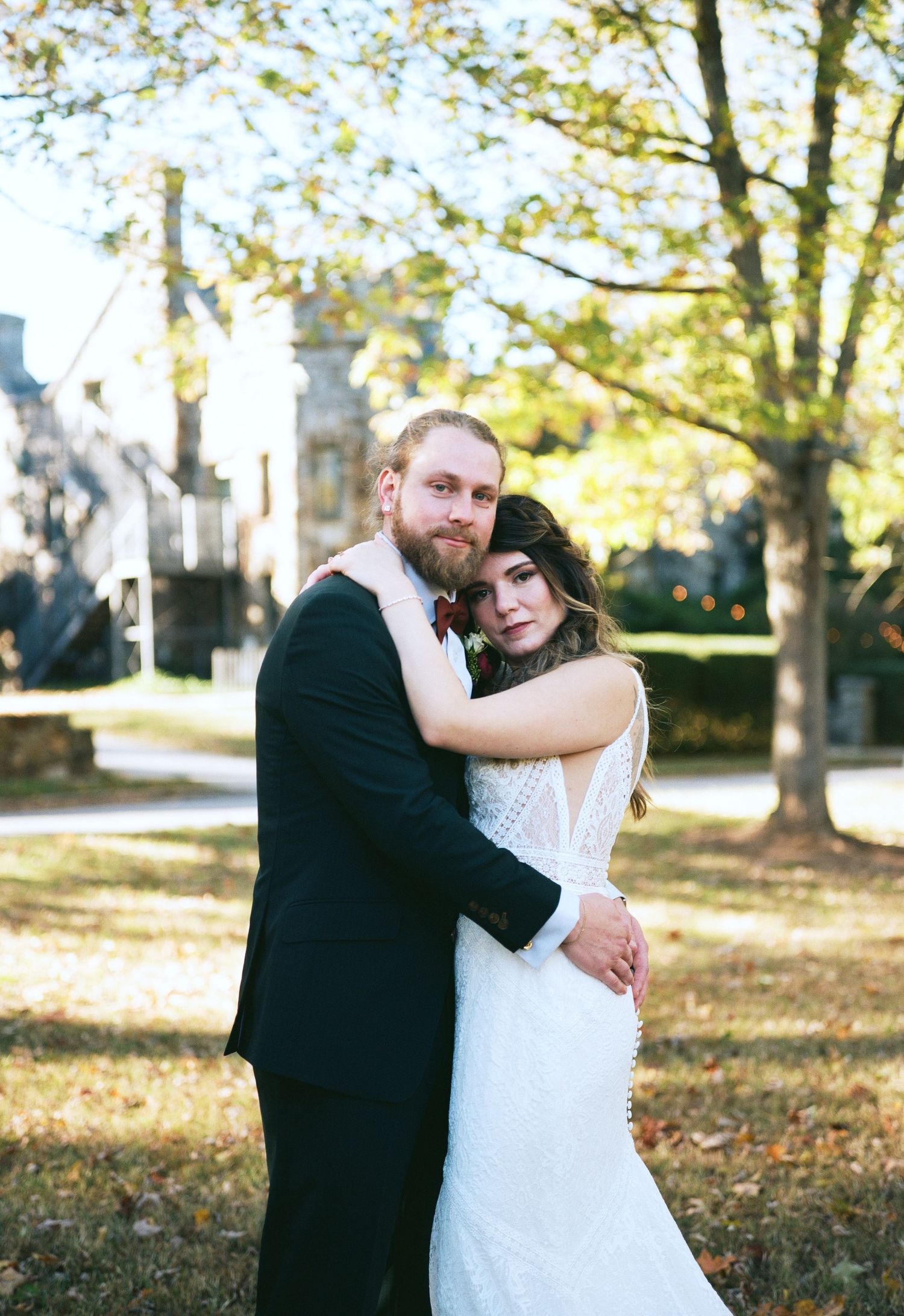 A bride and groom embrace in a lush, wooded setting.
