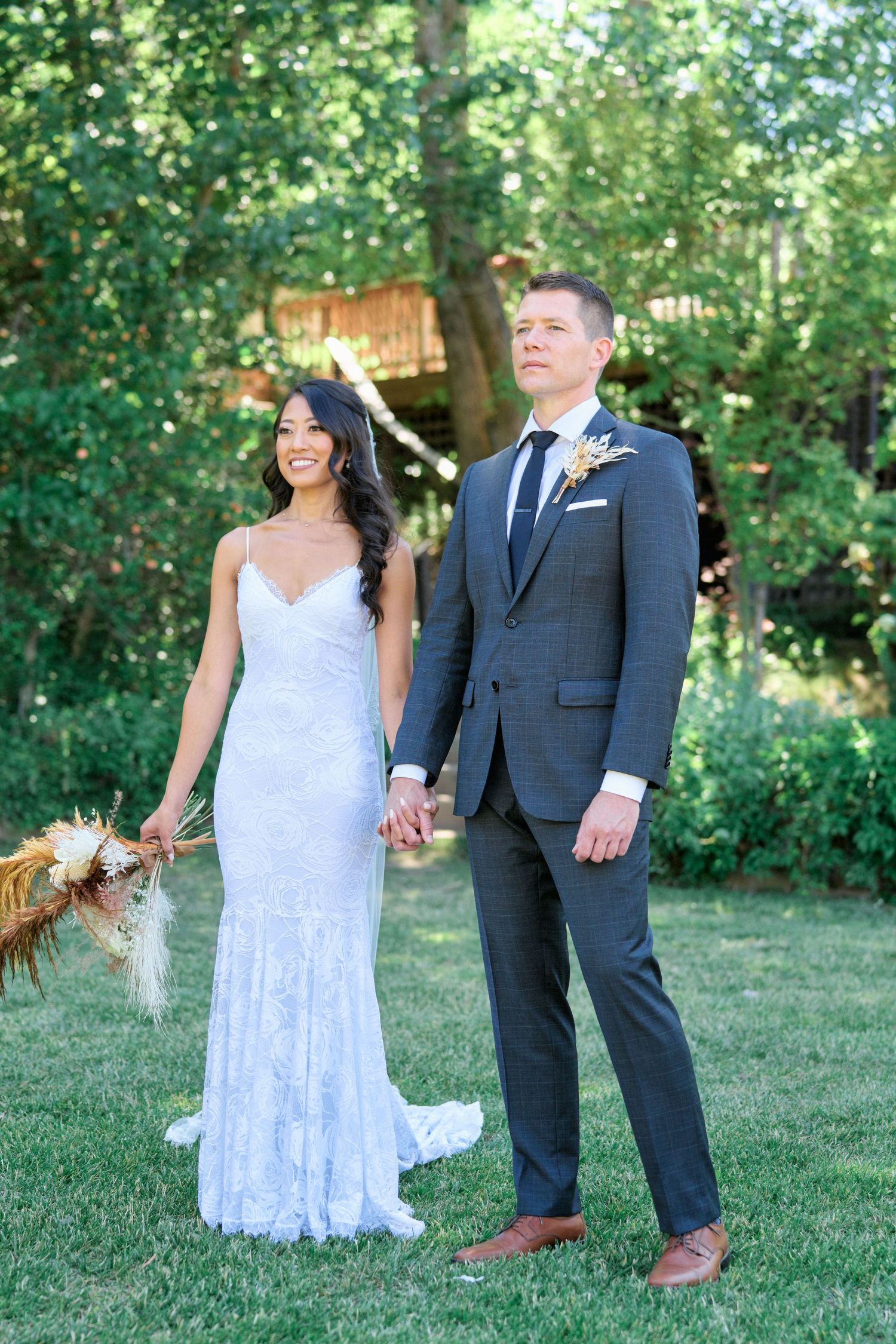 A newlywed couple poses together in a garden setting during their wedding day.