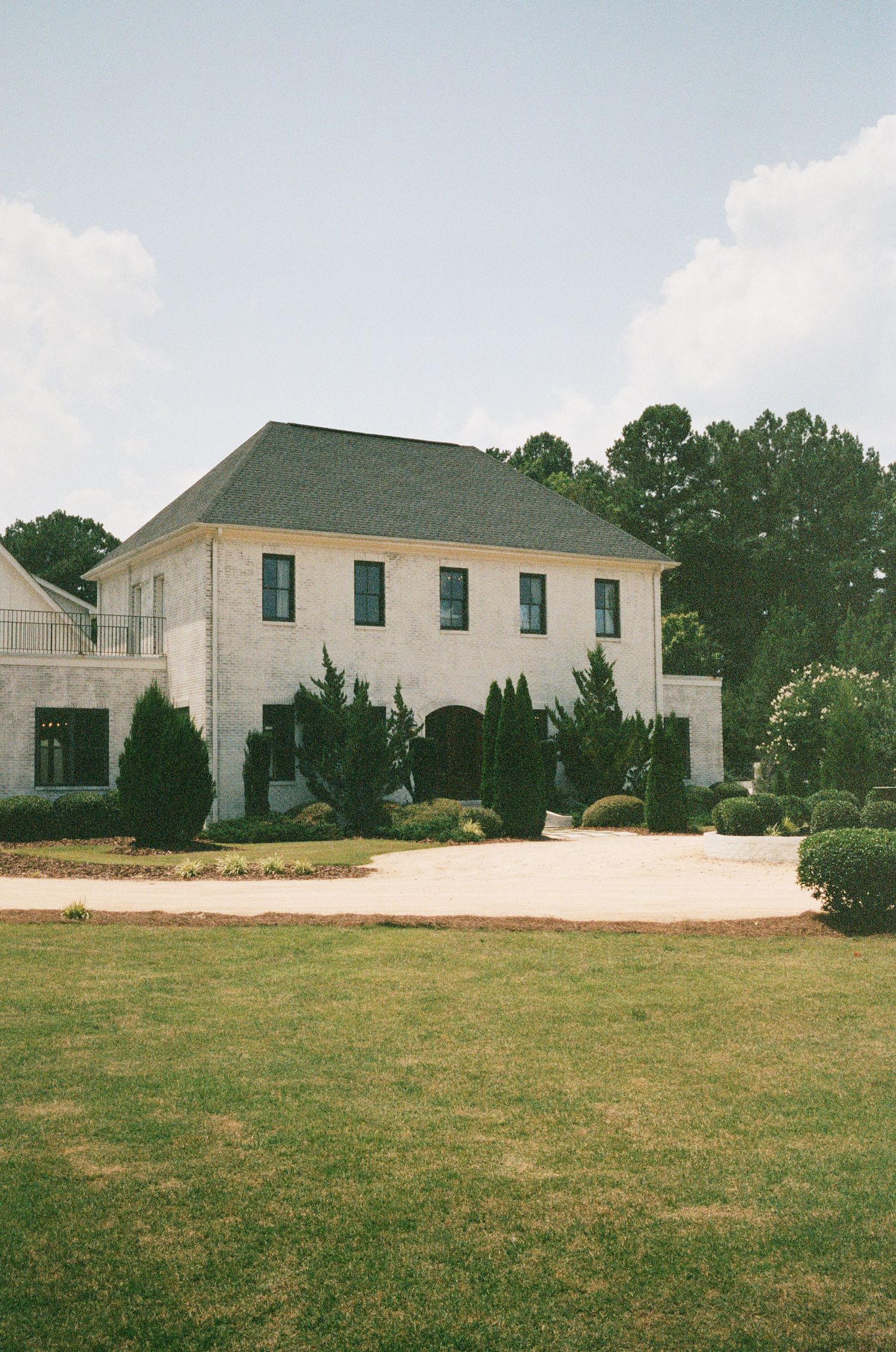 Elegant white stone building with green roof and manicured lawn.