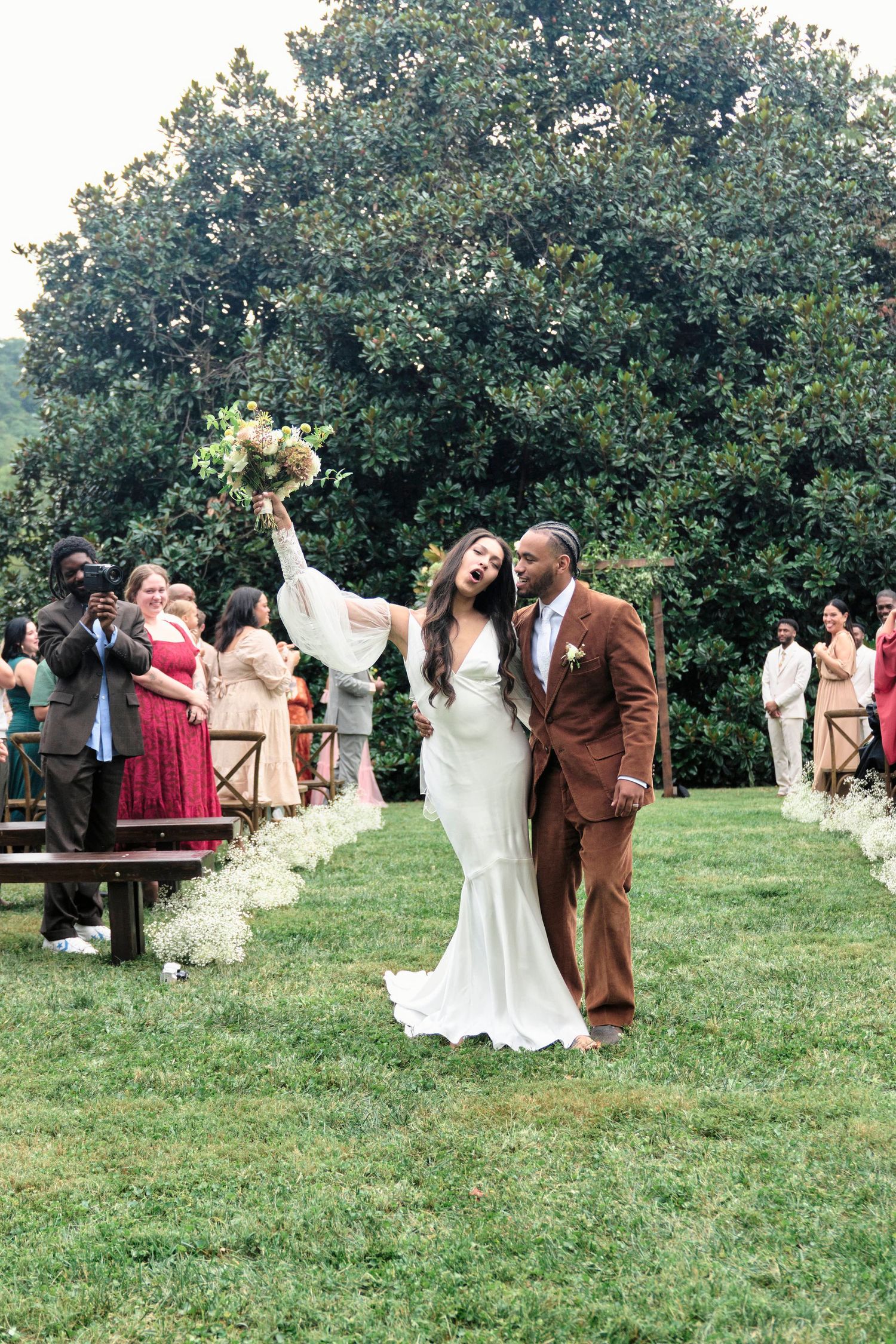Newlyweds celebrate down aisle at outdoor garden wedding with guests on both sides.