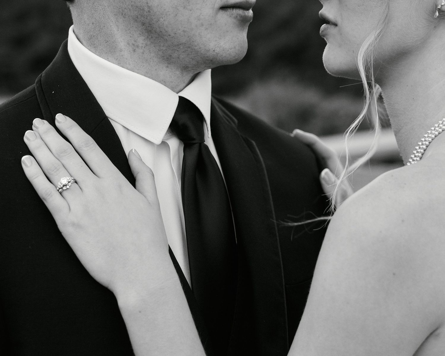 Close up black and white photos of romantic wedding couple embracing in formal attire.