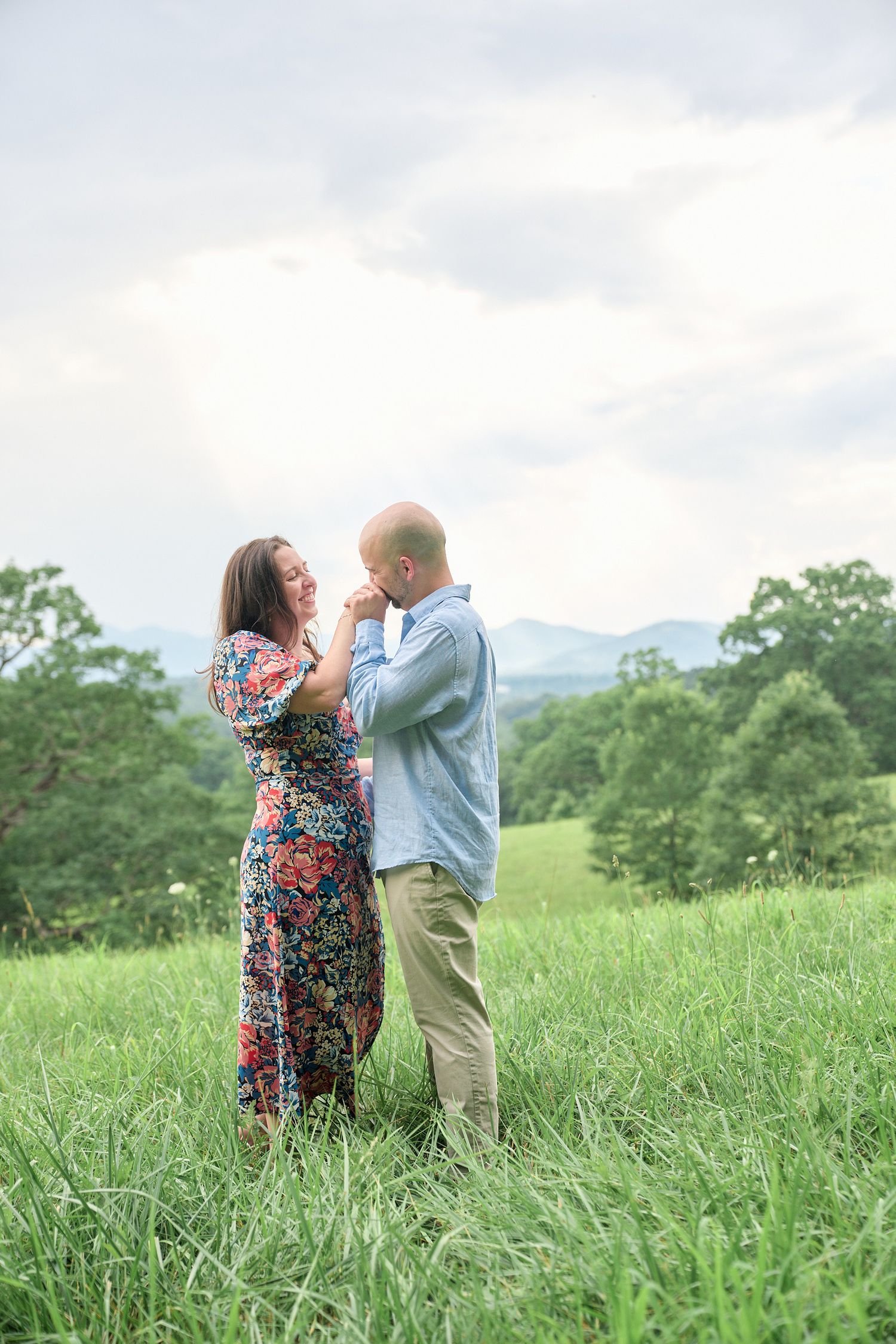 Tender moment between couple standing in mountain meadow during sunset.