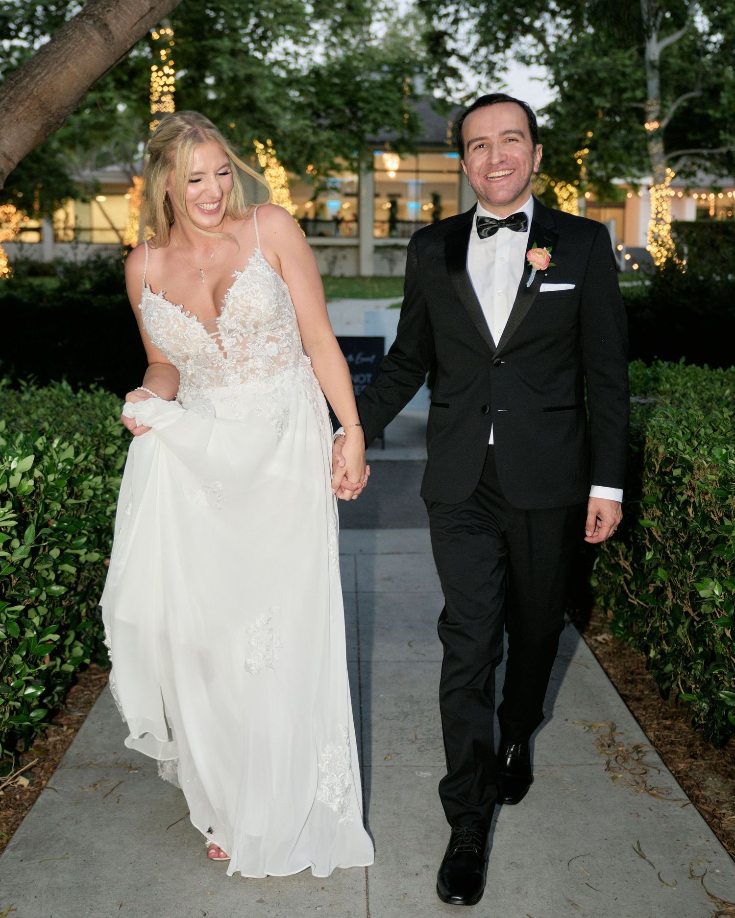 A couple walking together on an illuminated pathway during their wedding celebration.
