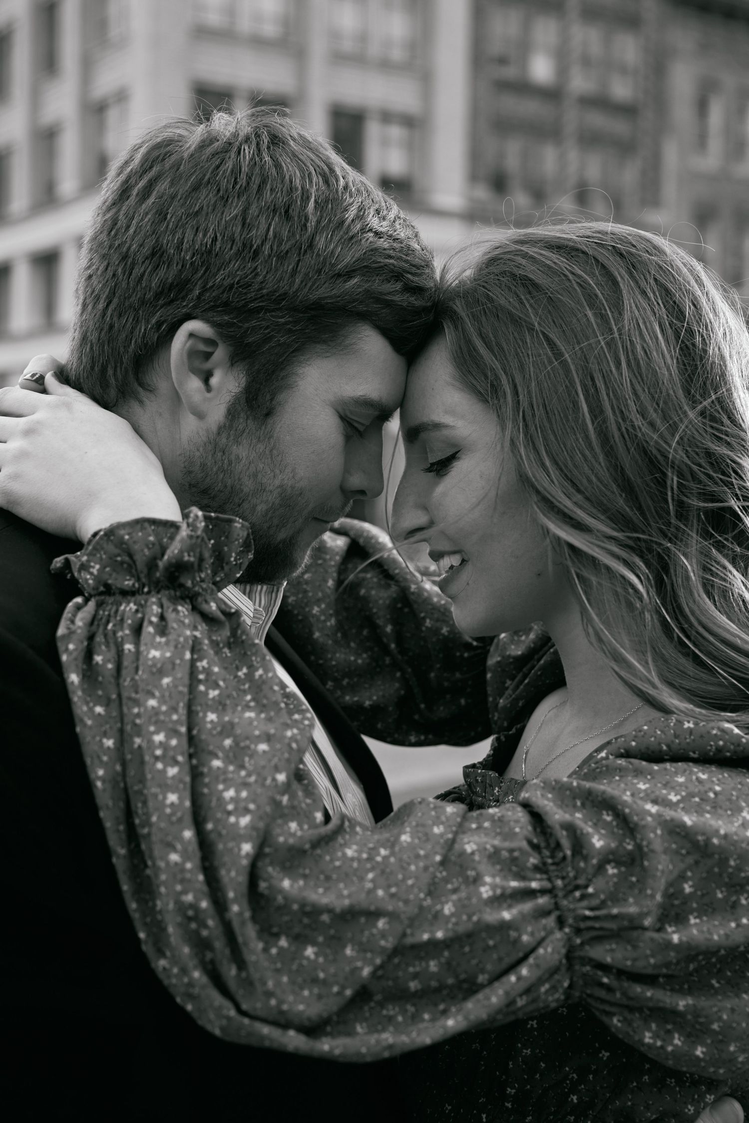 An intimate black and white portrait of a couple in a close embrace.
