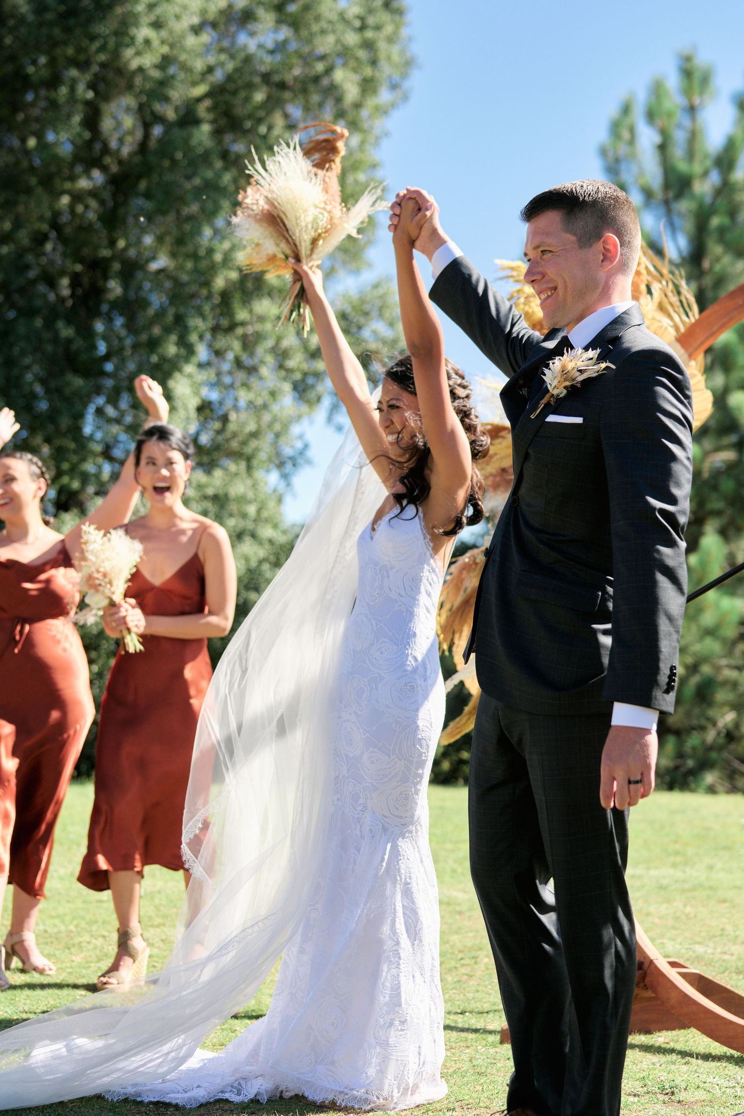 A joyful celebration moment during an outdoor wedding ceremony with guests cheering.