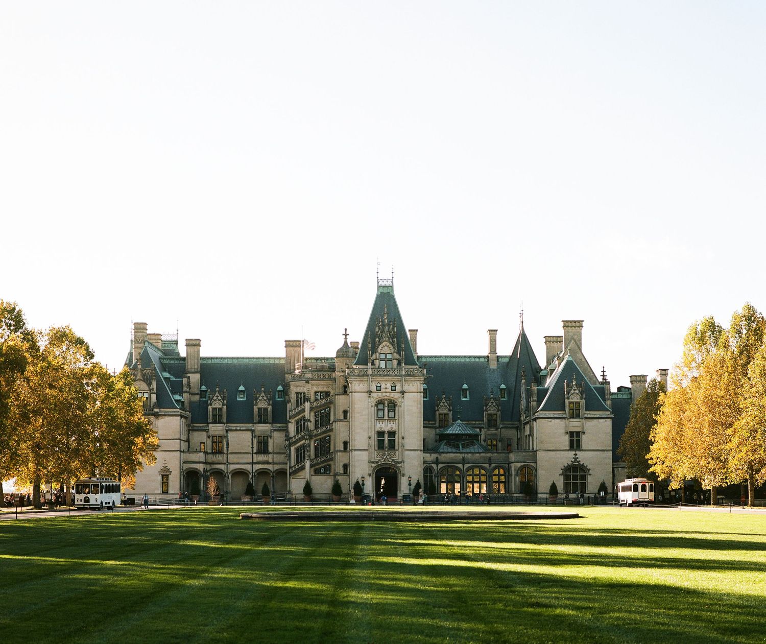 Photo of the Biltmore Estate house during the fall with yellow tress around  the house.