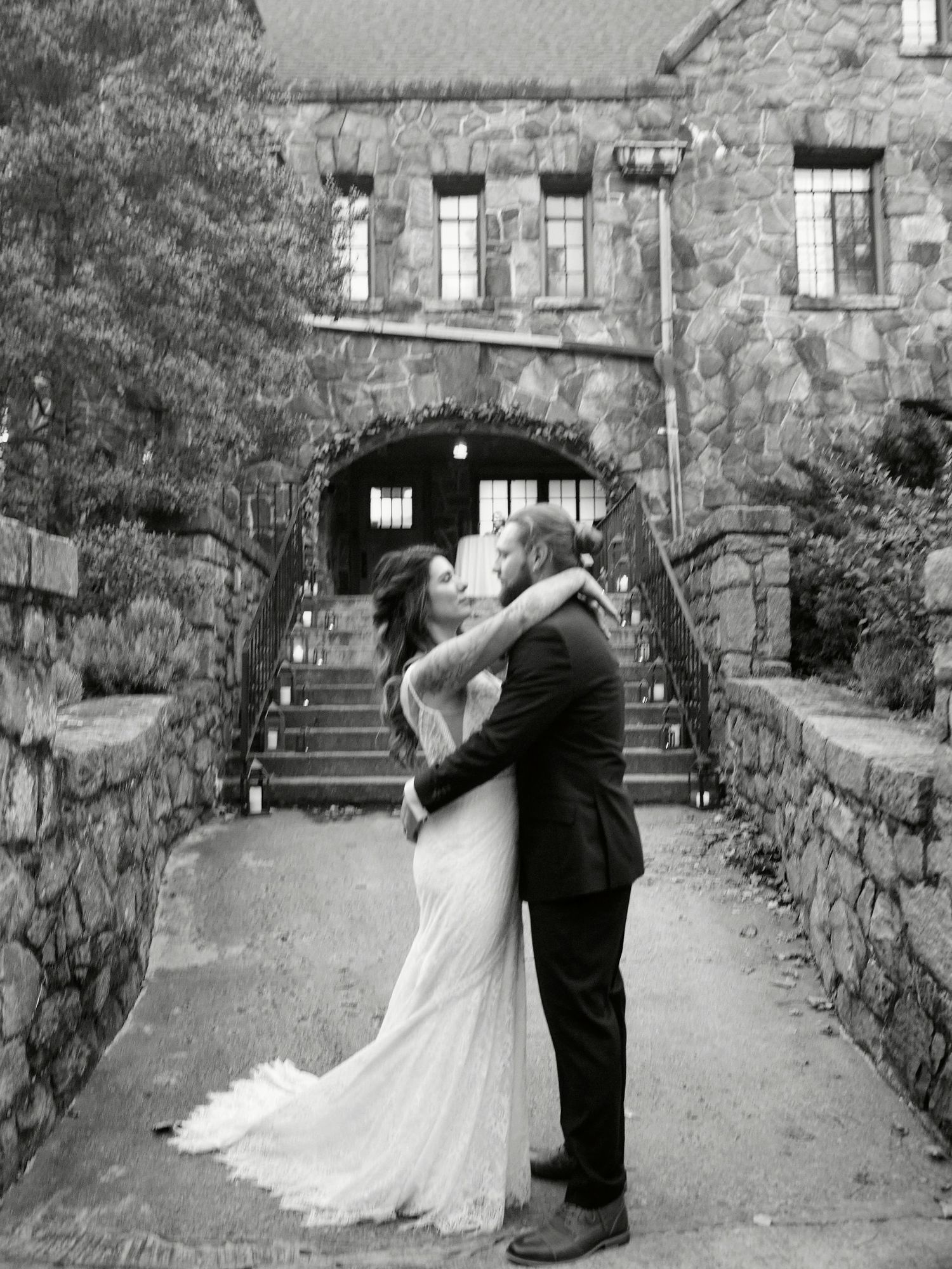 Black and white romantic portrait in front of a stone castle entrance.