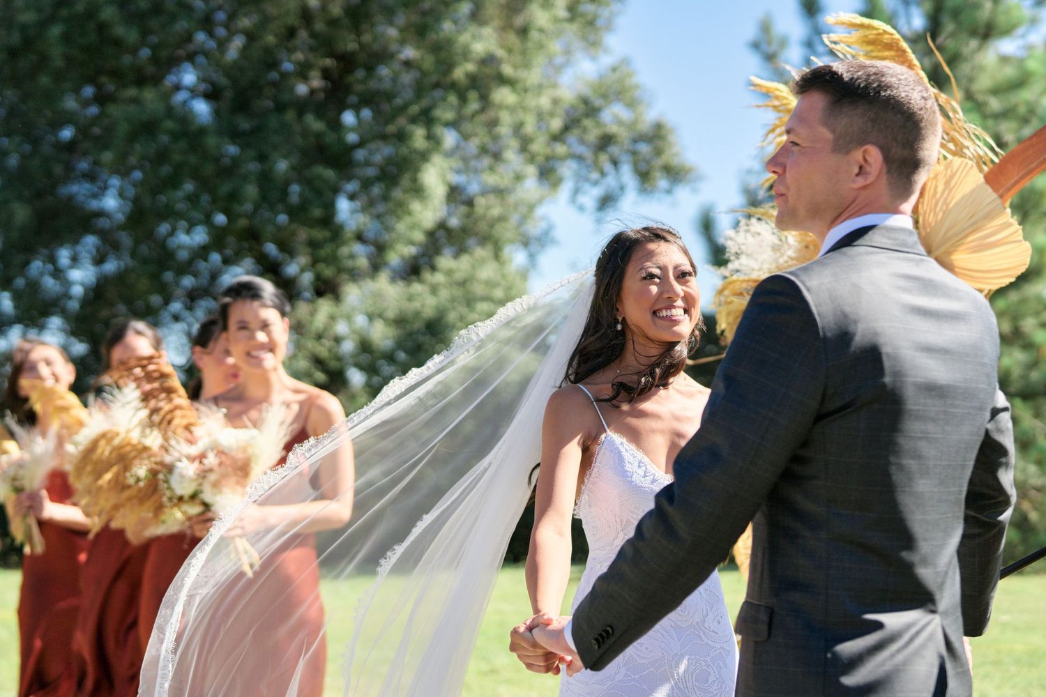 Joyful outdoor wedding ceremony with dried floral decorations and natural lighting.