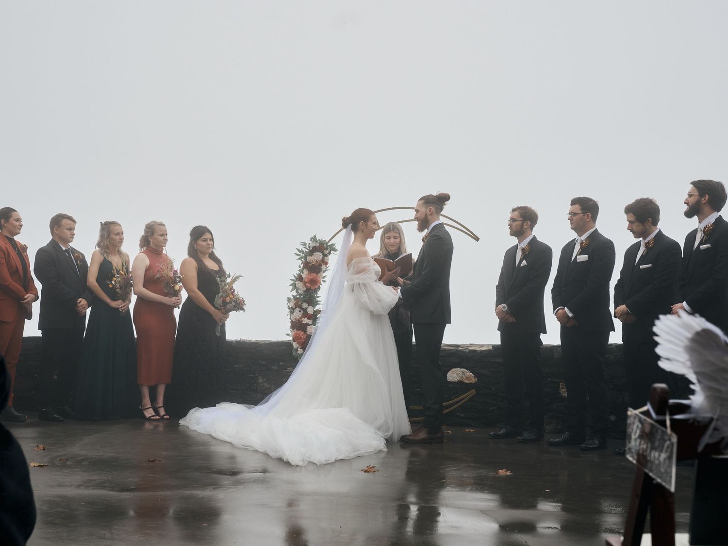 A wedding ceremony with bridal party and groomsmen lined up in foggy weather.