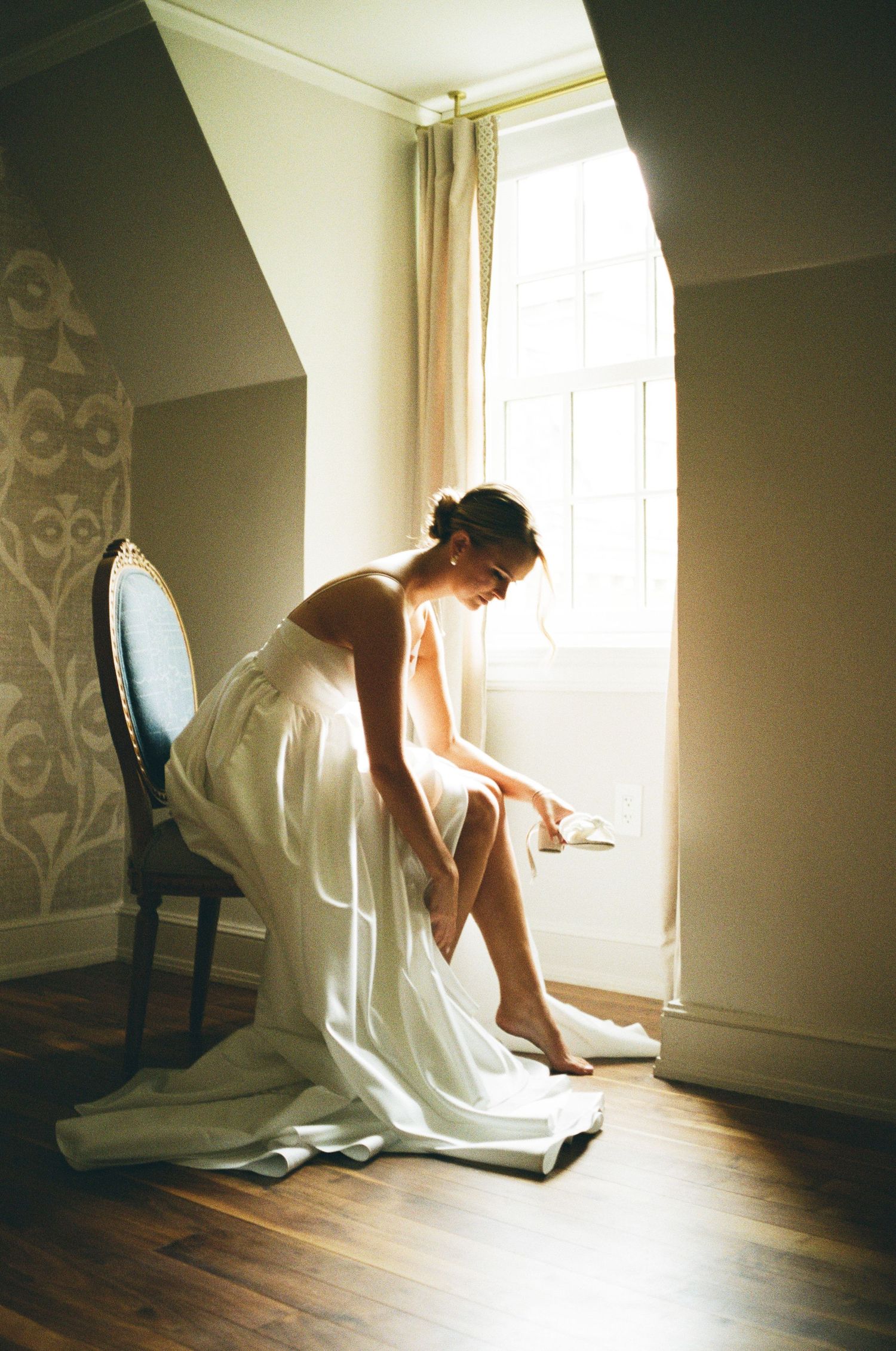 A sequence of dreamy photos shows a bride in white dress bending down in sunlit room with wooden floors.