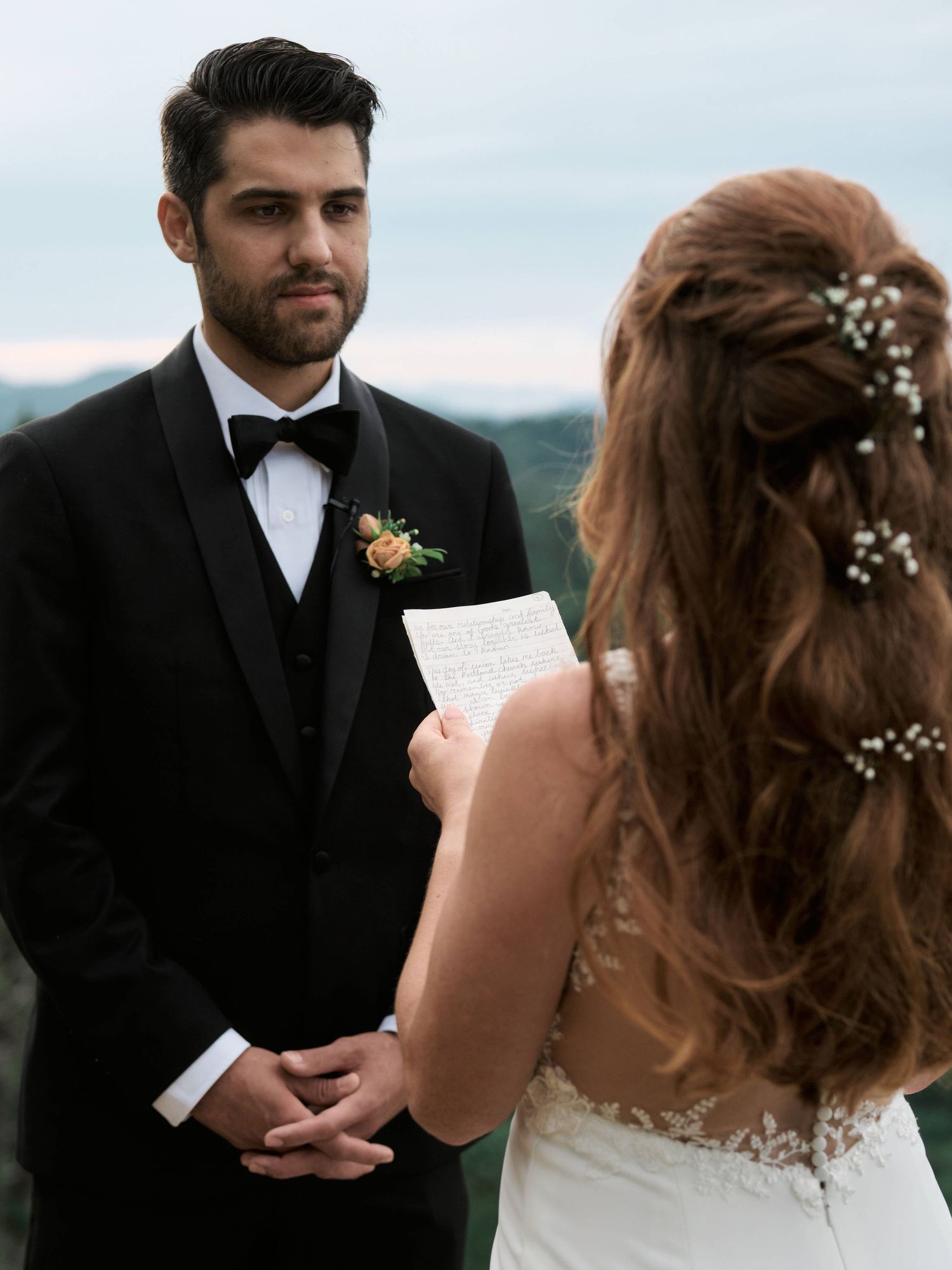 A couple exchanges vows during an intimate outdoor wedding ceremony against a scenic mountain backdrop.