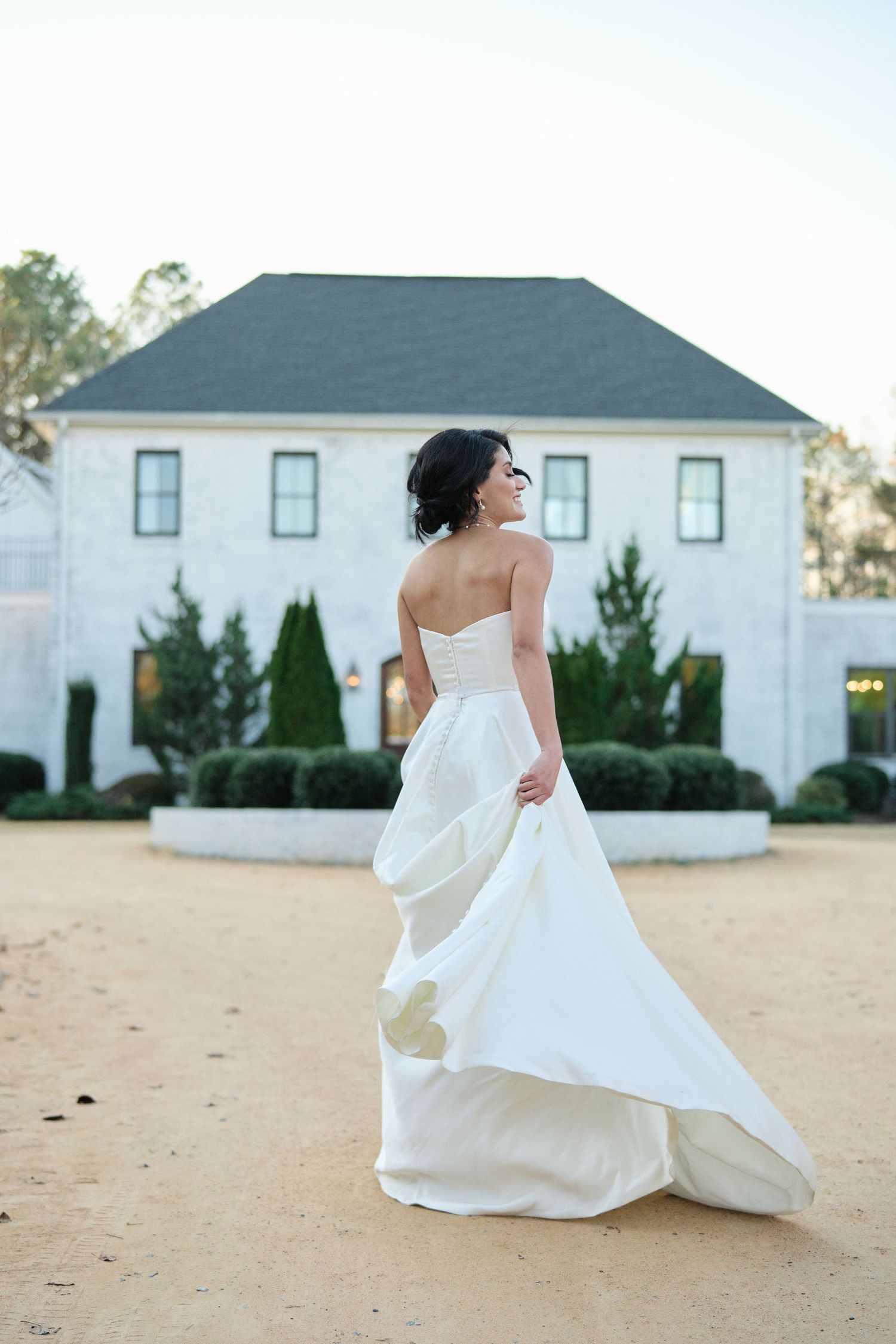 Bride smiling walking outside the venue swinging her dress during an outdoor wedding in Raleigh, NC.