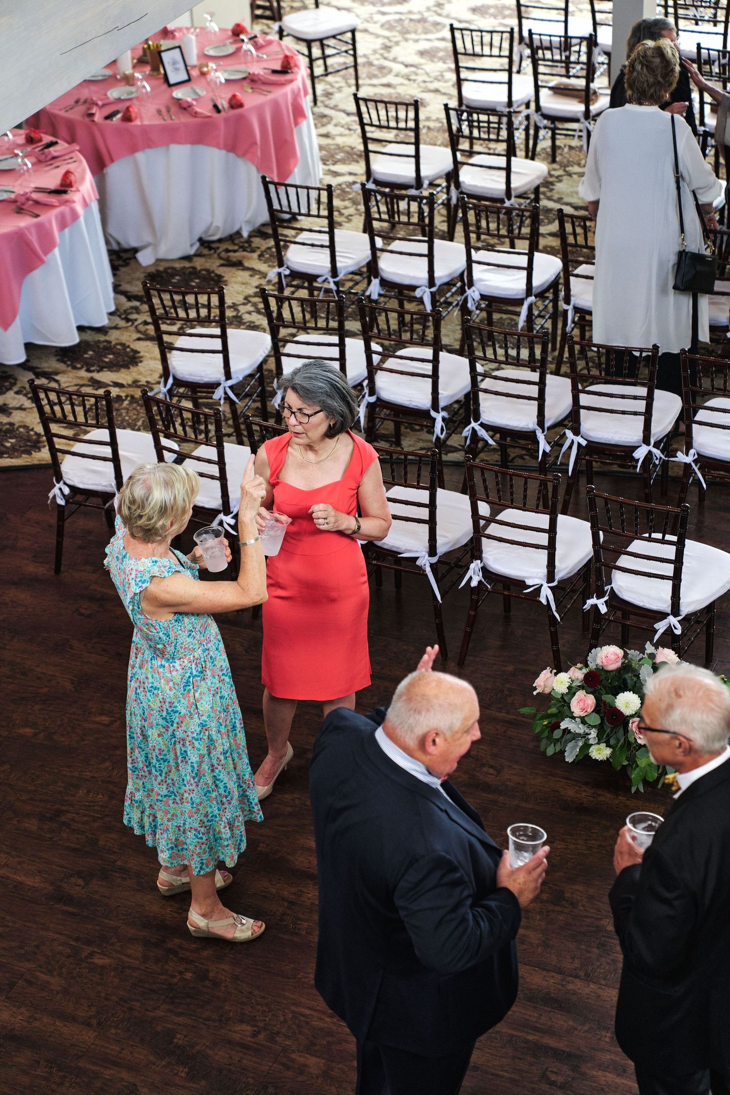 Wedding reception setup with Chiavari chairs and pink table linens in an indoor venue.