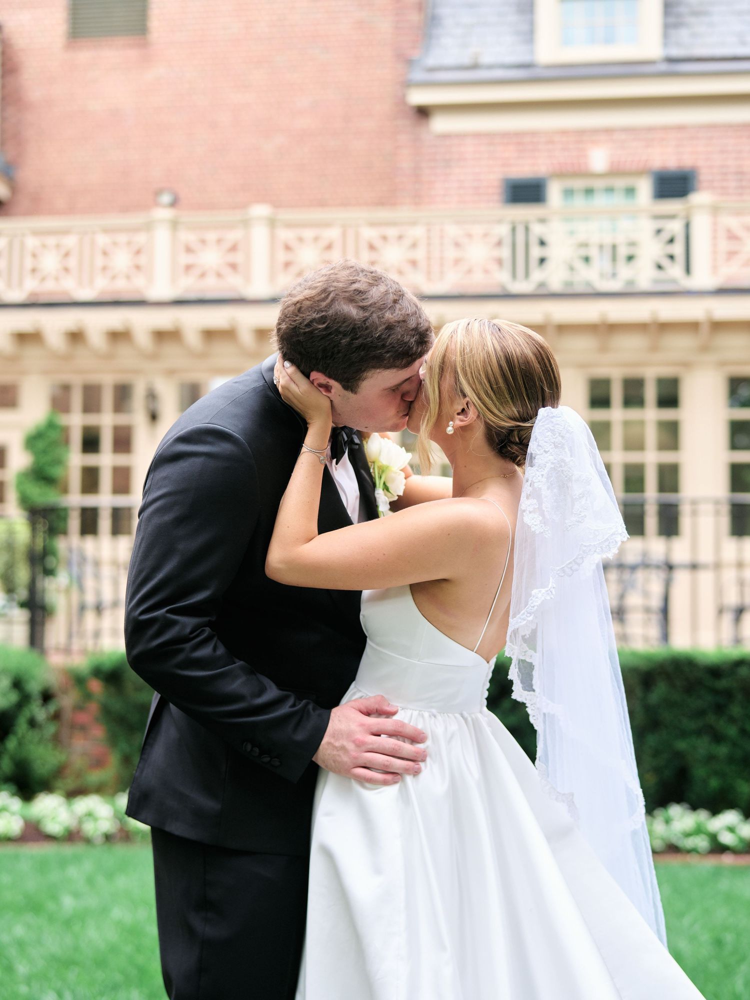A tender wedding moment captured between newlyweds in formal attire embracing outdoors.