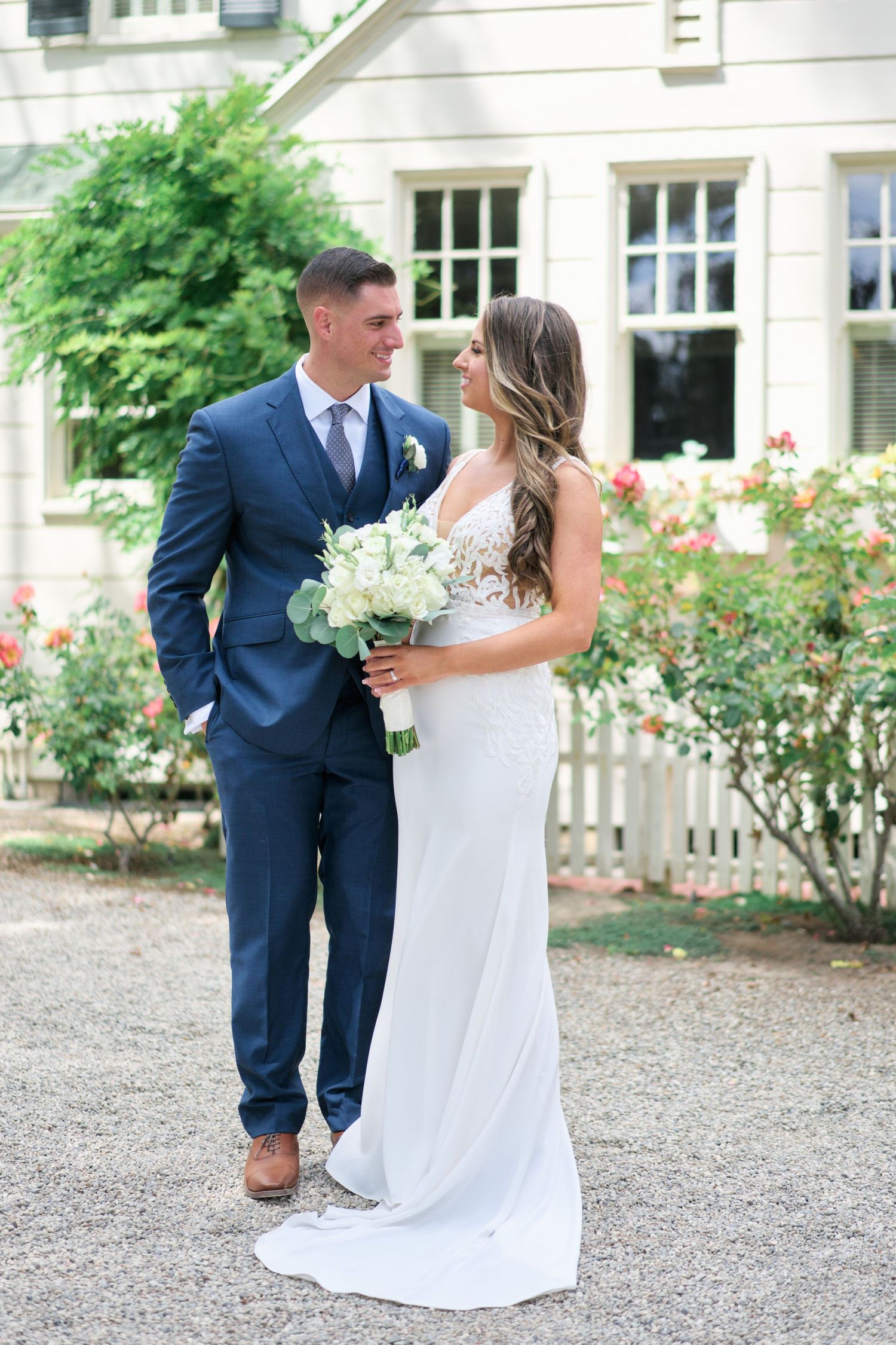 Couple shares intimate moment in formal attire in front of classic white house.