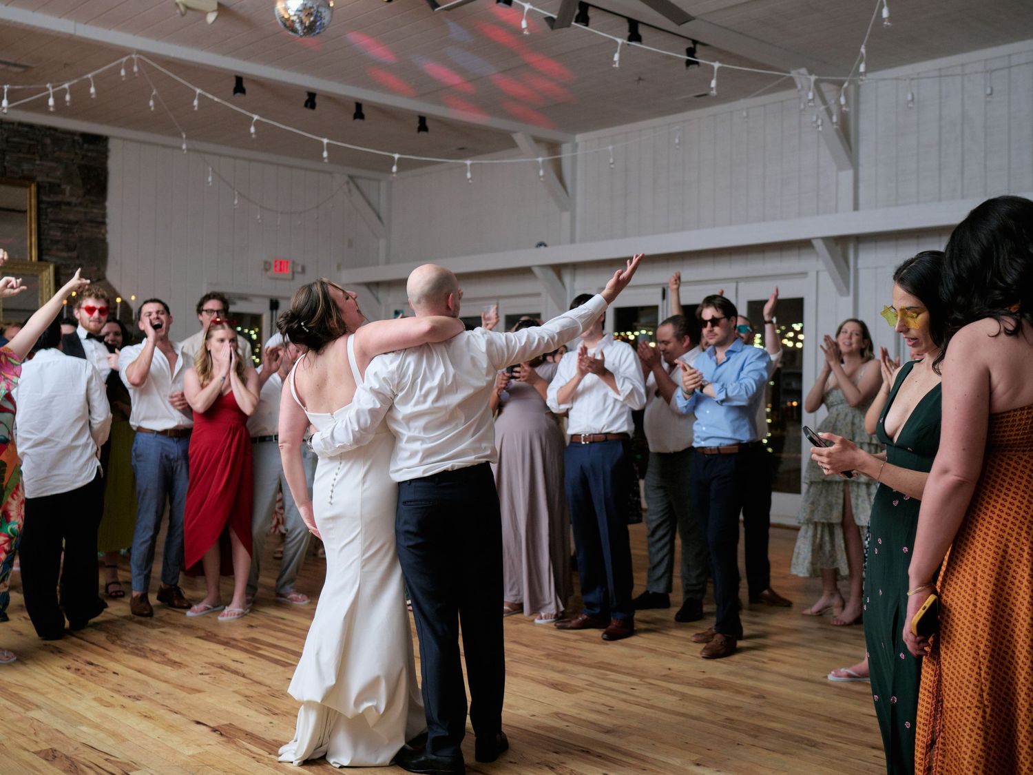 Wedding guests gather around the dance floor to celebrate the newlyweds.