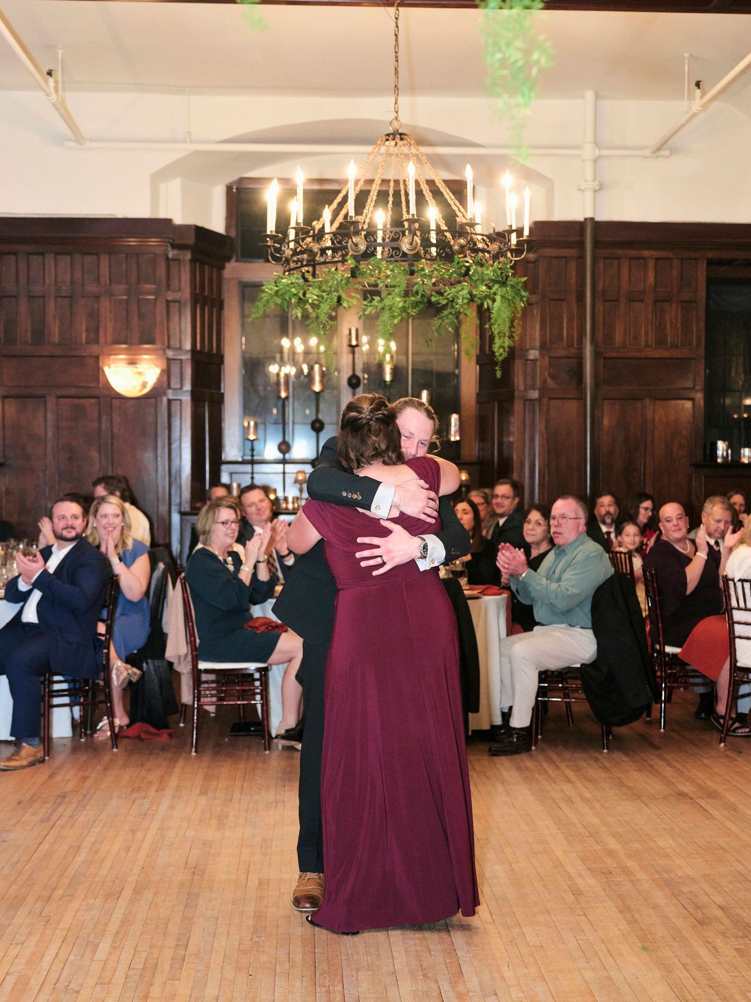 A couple sharing an intimate dance under a chandelier at a wedding reception.