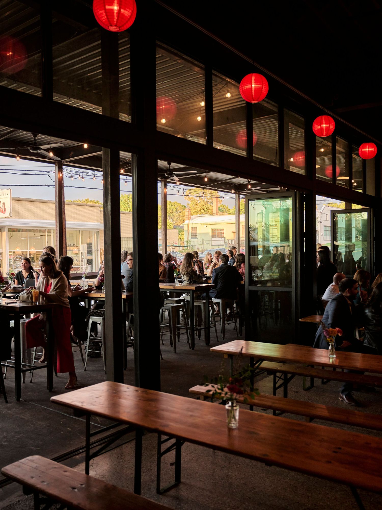 An evening reception venue with red paper lanterns and communal dining tables.