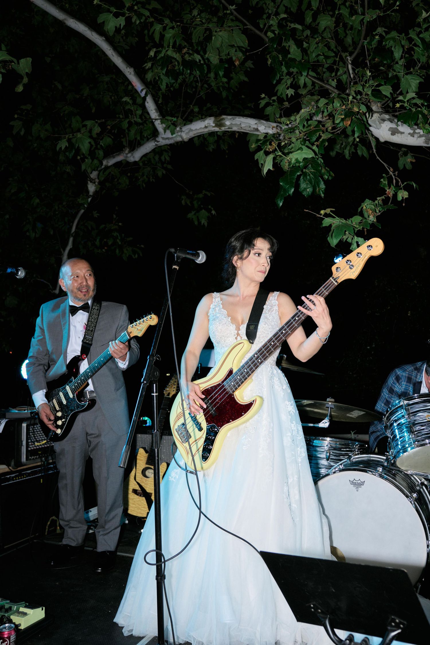Band performing at night with musicians playing guitars on outdoor stage.