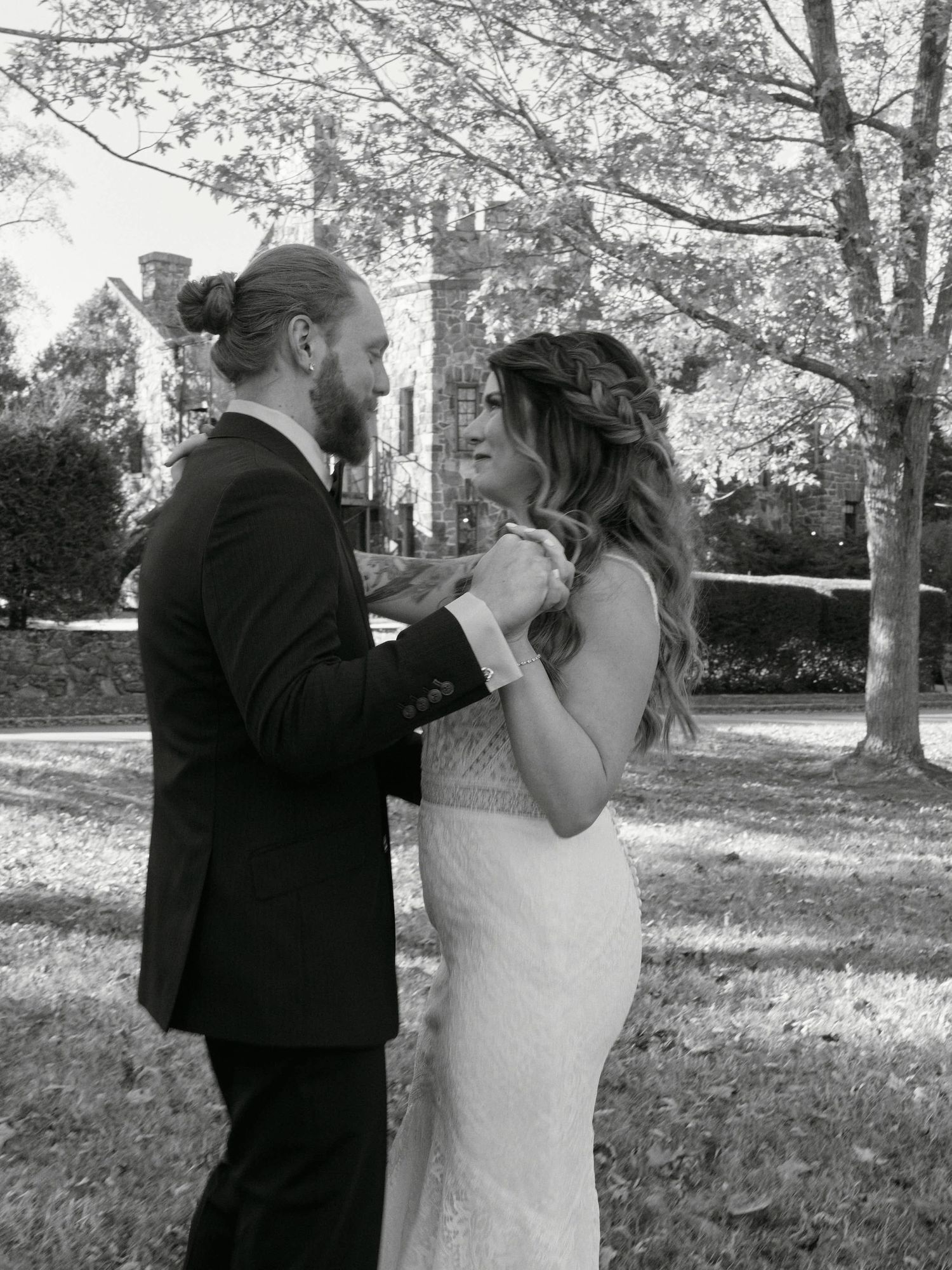 Black and white photo of couple sharing intimate moment at castle grounds.