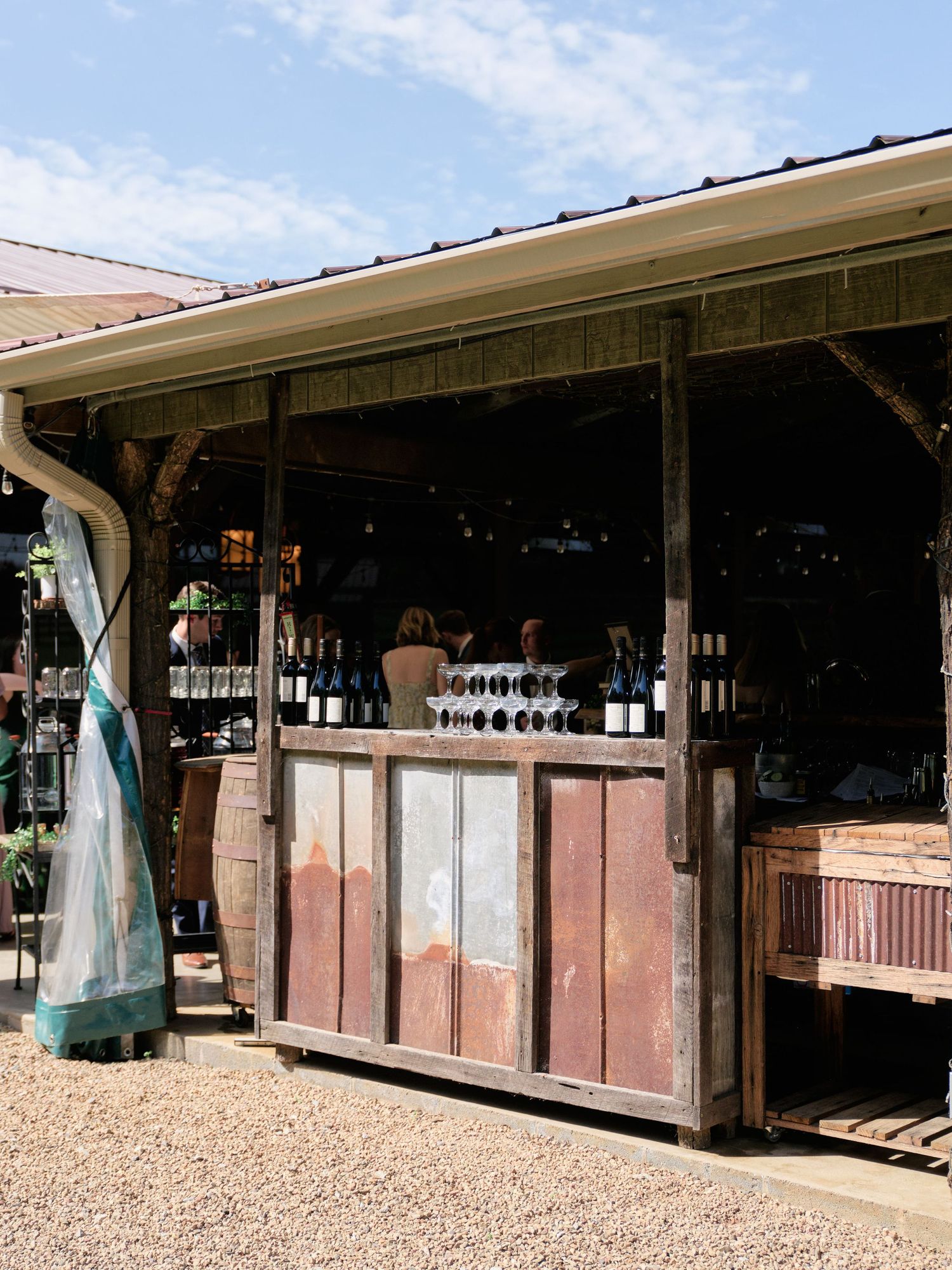 A rustic outdoor bar setup with wooden panels and wine bottles on display.
