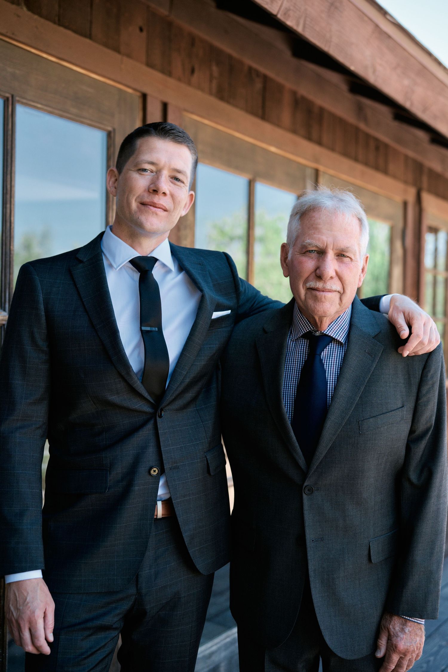 Two generations pose together in matching dark suits and ties.