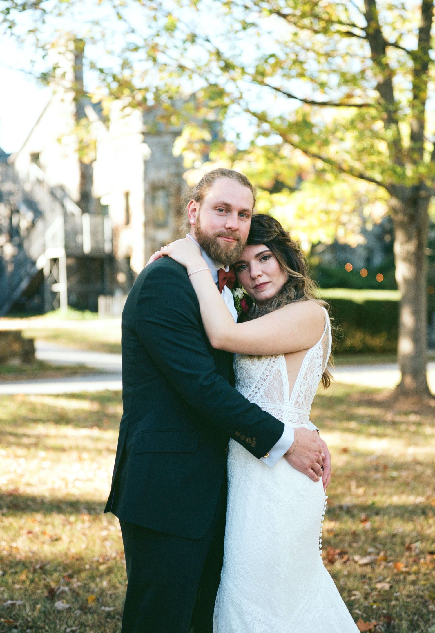 Newlywed couple embraces outdoors during autumn wedding photoshoot.