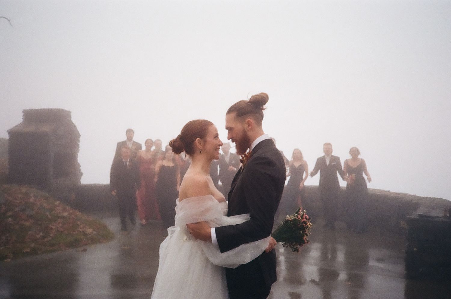Newlyweds share romantic moment on foggy outdoor terrace during wedding celebration.