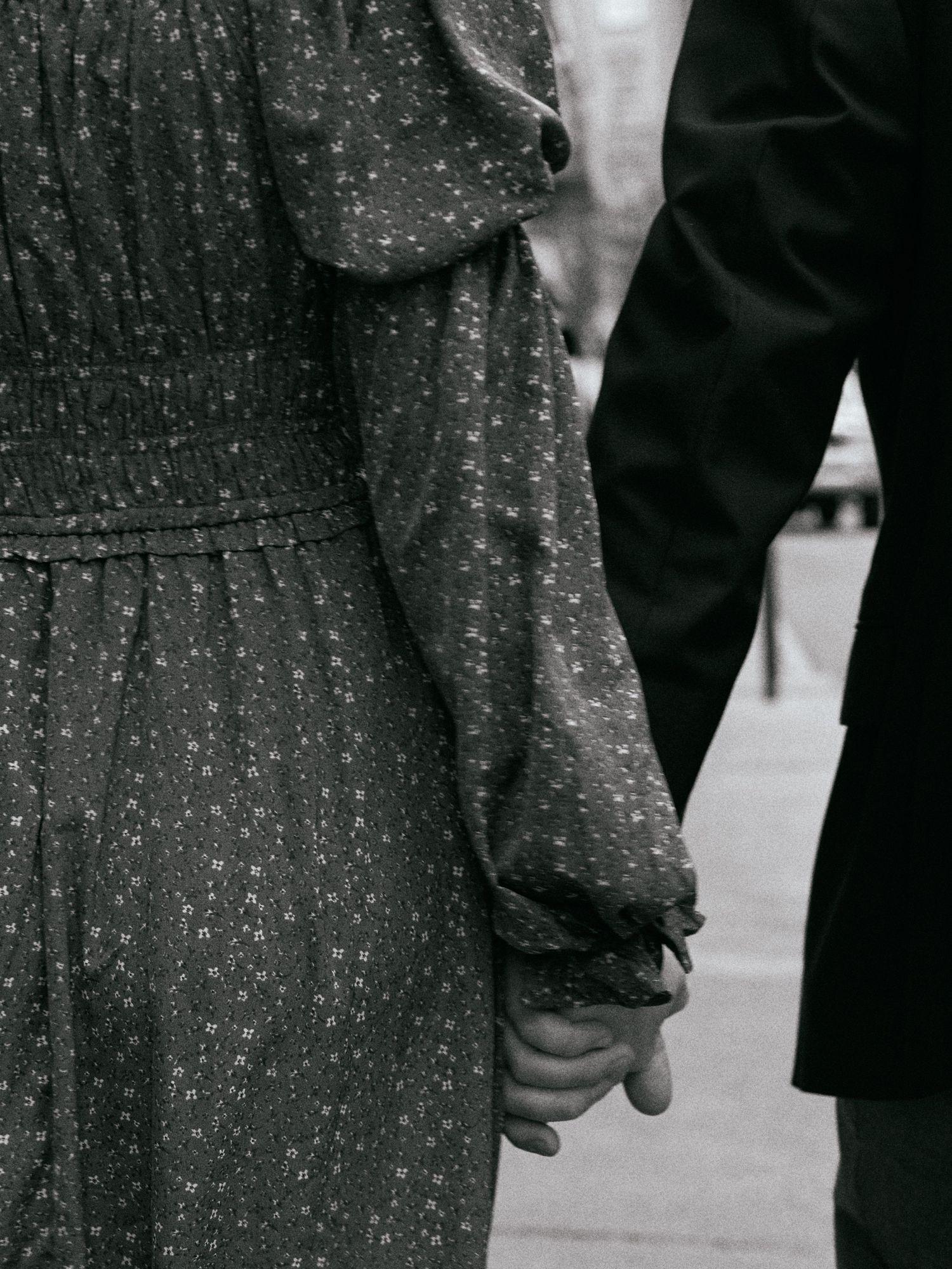 A black and white detail shot of hands holding while wearing formal attire.