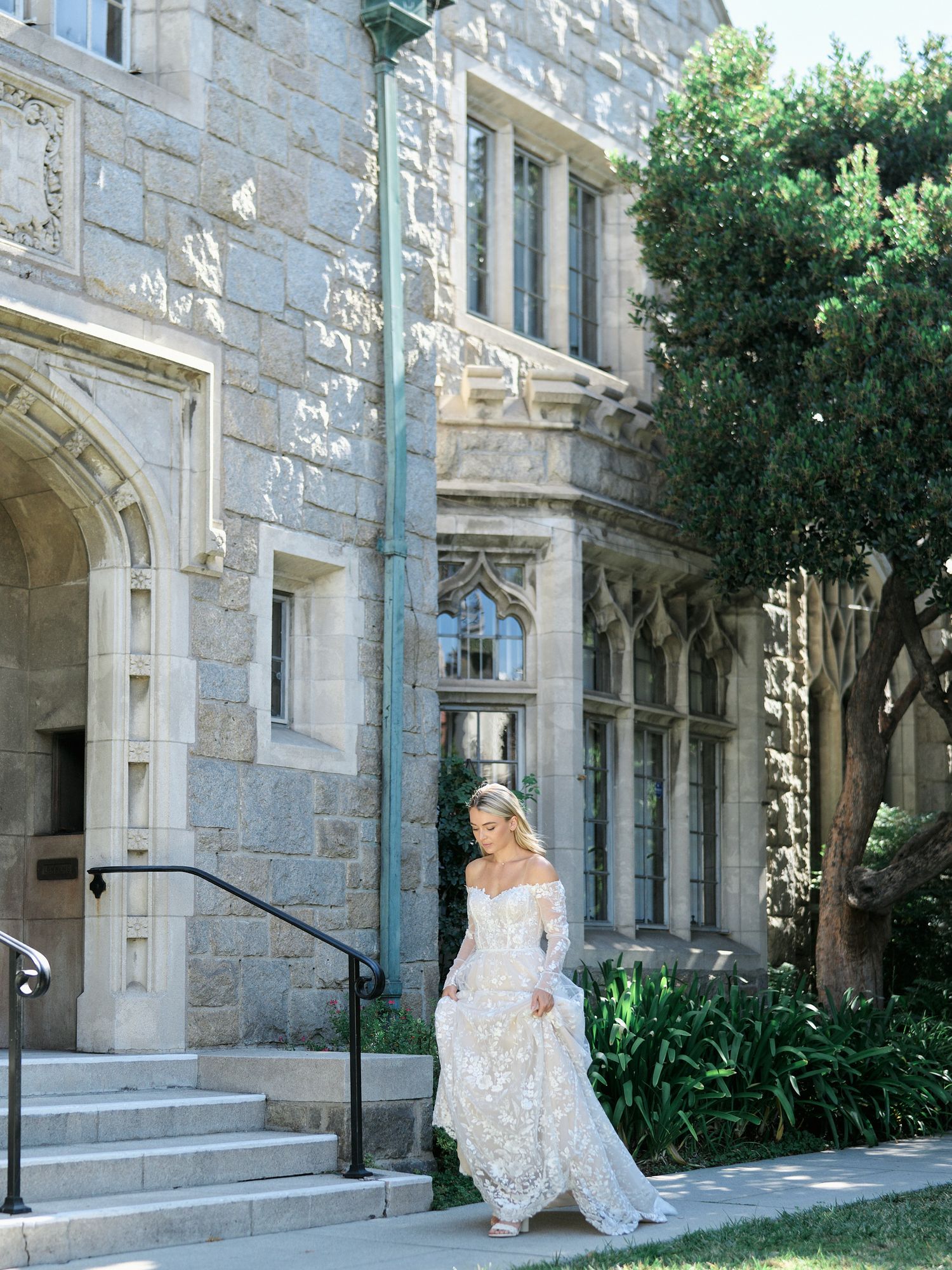 Romantic bridal portrait at gothic stone building with lush garden landscaping.