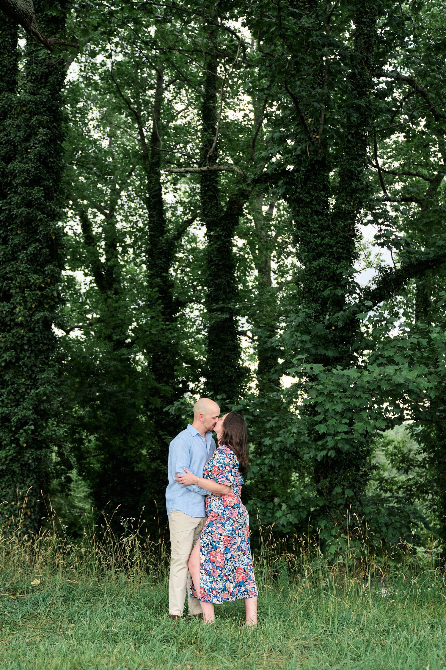 Couple sharing intimate moment against backdrop of lush forest trees.