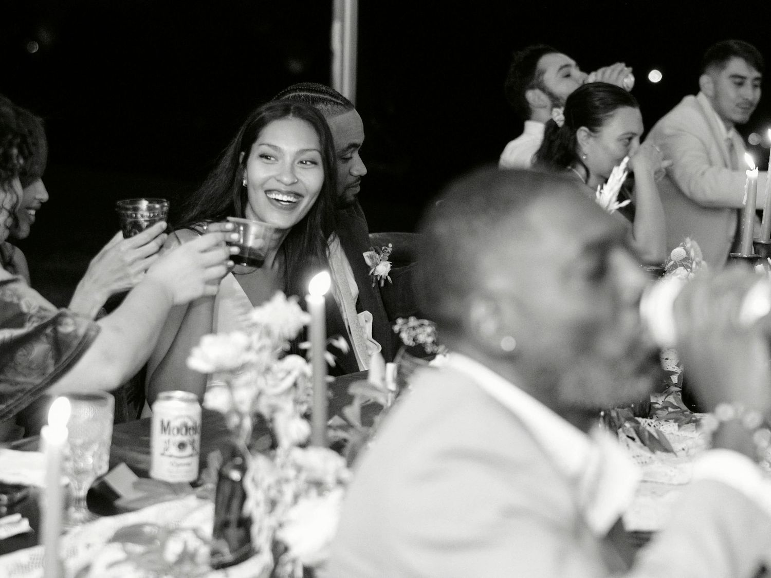Wedding guests laughing and celebrating at an outdoor reception dinner.