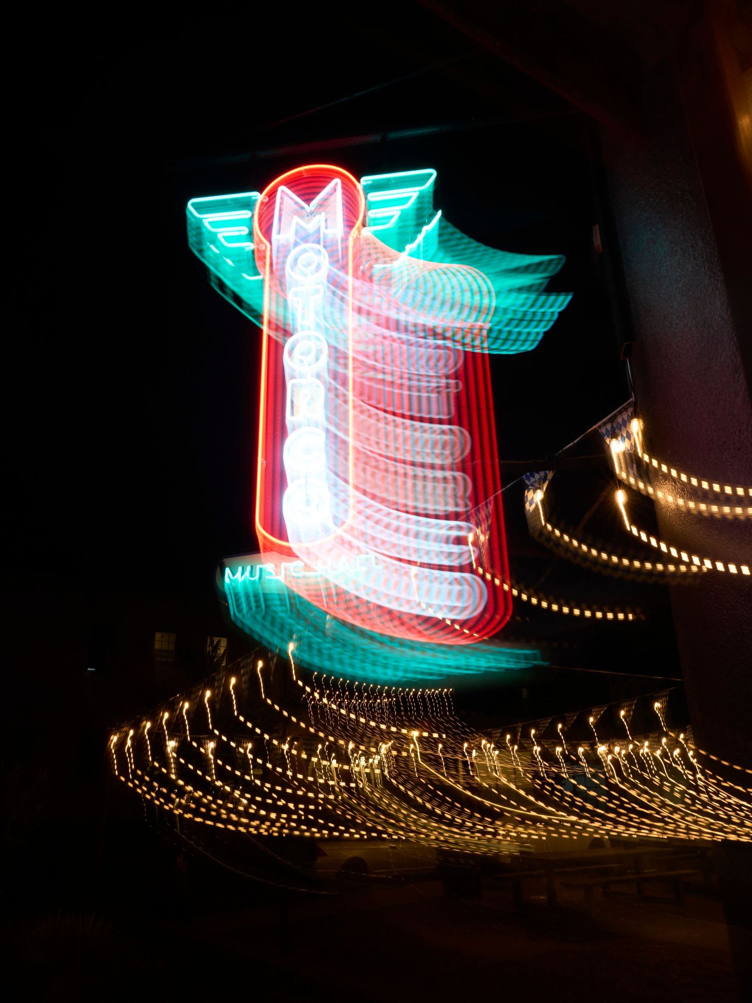 A retro-style neon sign glows in pink and turquoise against a dark background.