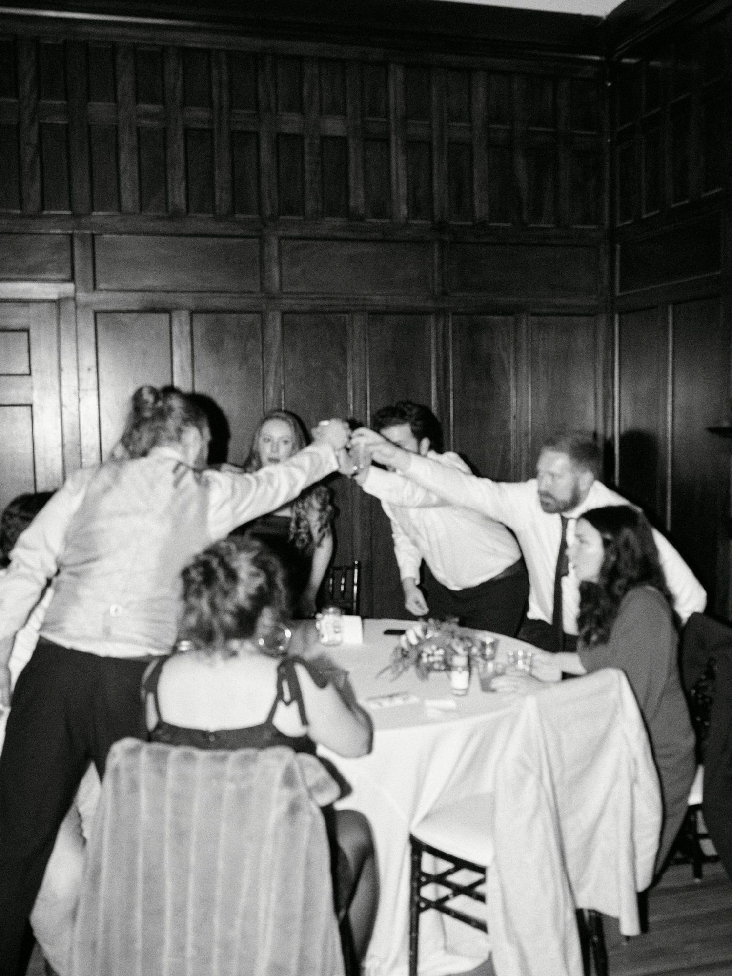 Vintage black and white photo of people toasting at a dinner party.