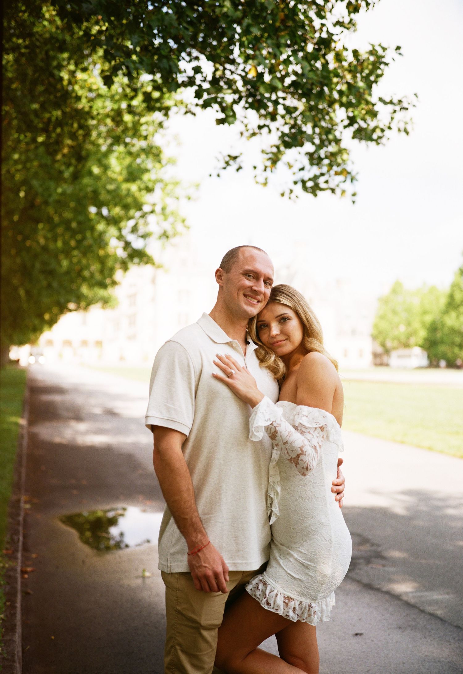 A couple embraces on a tree-lined path during a romantic outdoor photo session at golden hour.