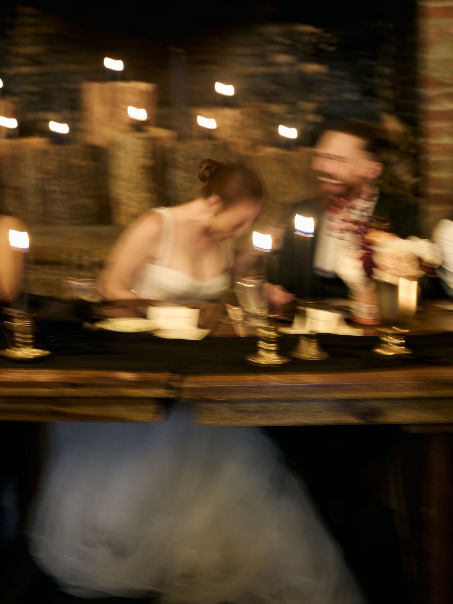 A blurred candlelit reception scene with a couple dining at their wedding.