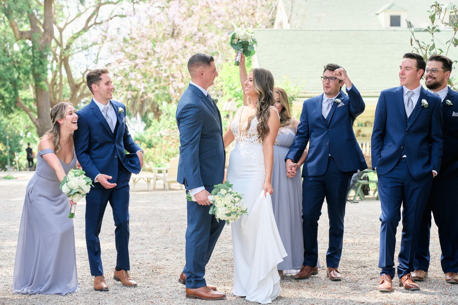 Wedding party poses casually outdoors with spring blossoms in the background.
