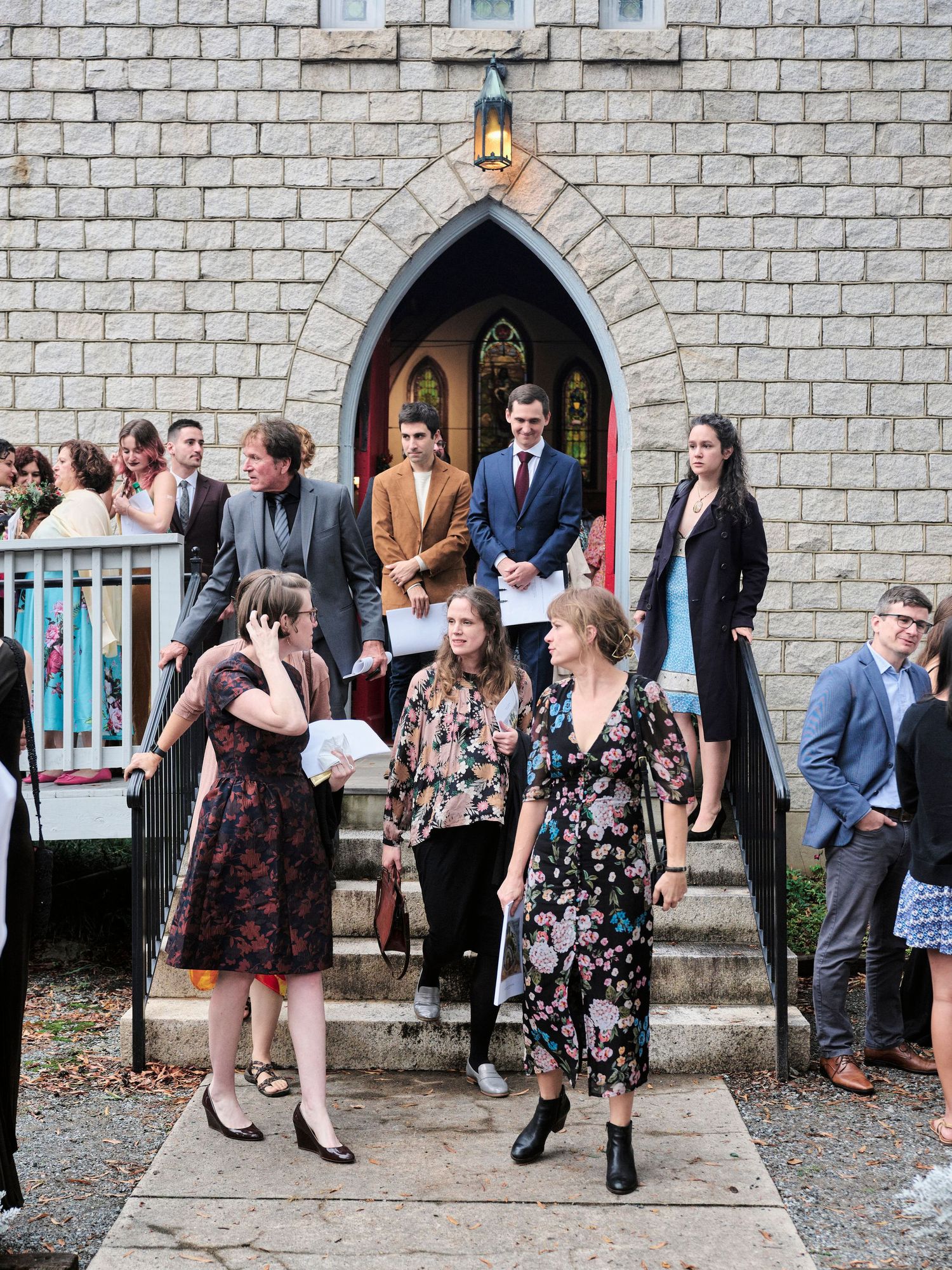 Wedding guests gather outside a stone church entrance with Gothic architecture.