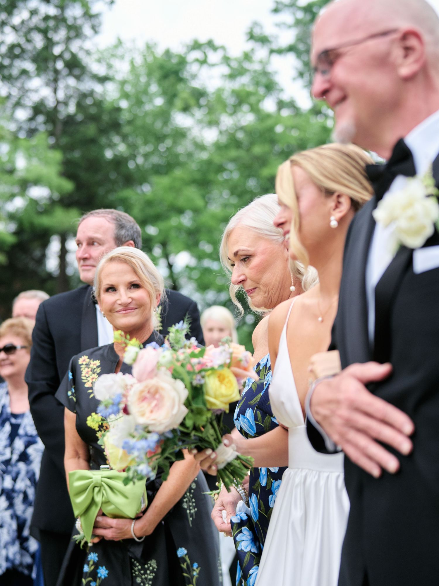 Wedding party members sharing emotional moments during outdoor ceremony.