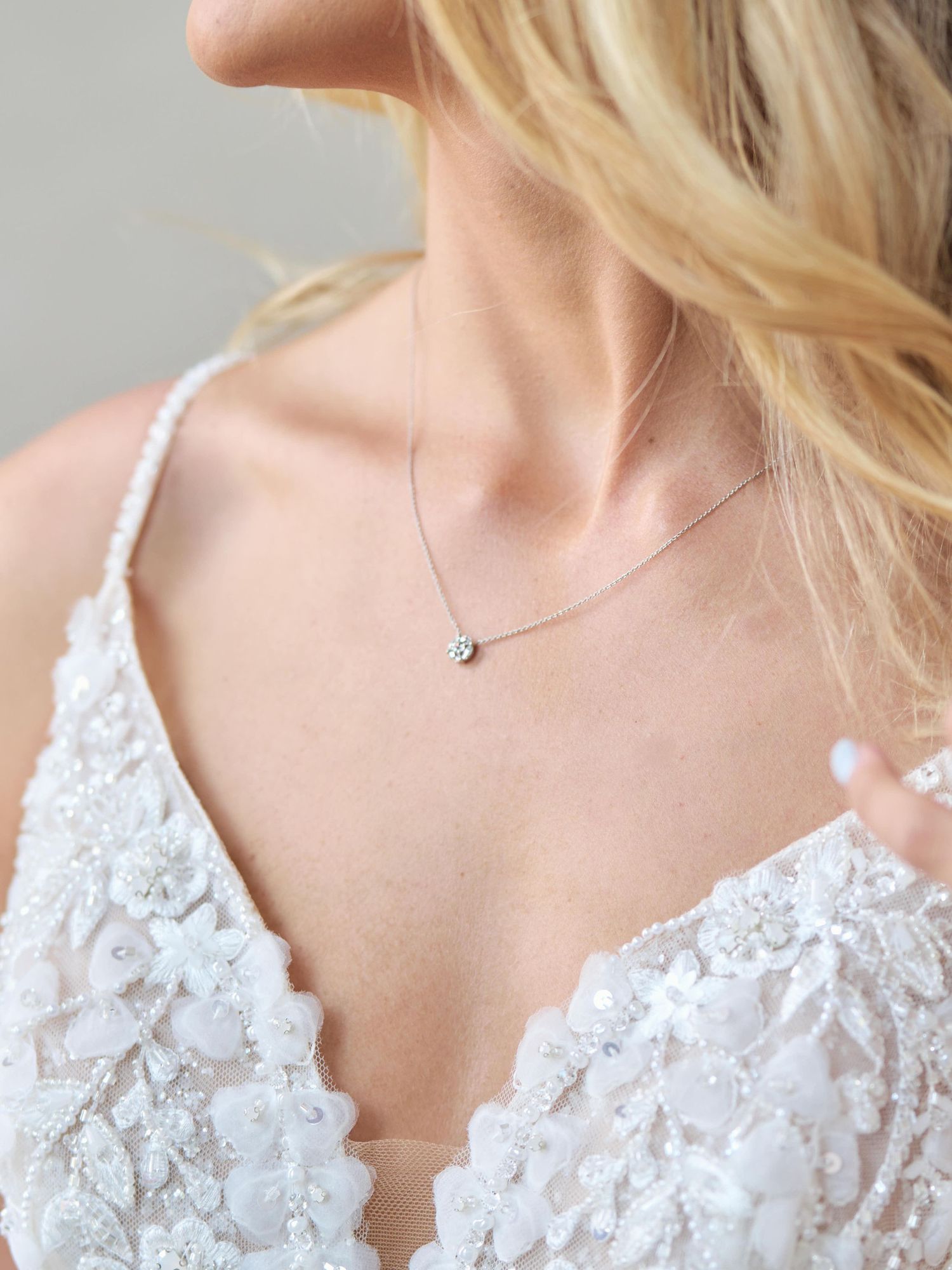Delicate bridal jewelry featuring a simple silver necklace with lace dress detail.