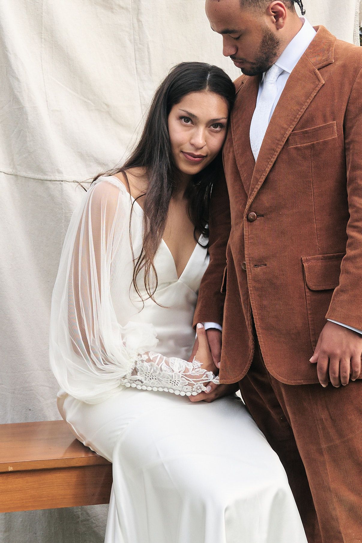 Intimate wedding portrait of couple against white backdrop with bride in flowing white gown.