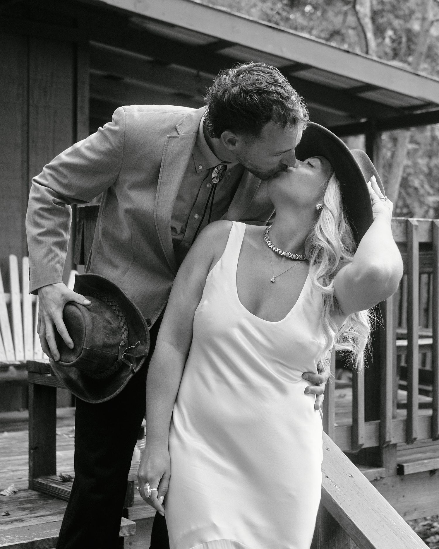 Black and white photo series showing a couple in romantic embrace and kiss on a wooden deck or porch.